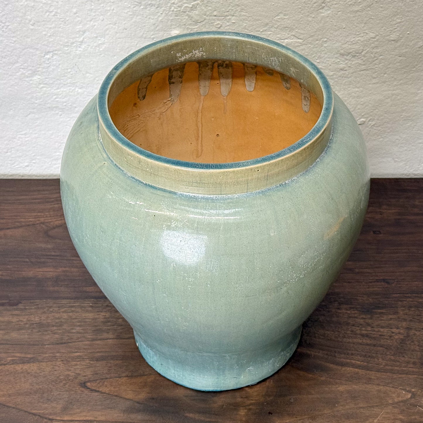 Light blue ceramic jar with a textured surface on a wooden surface.