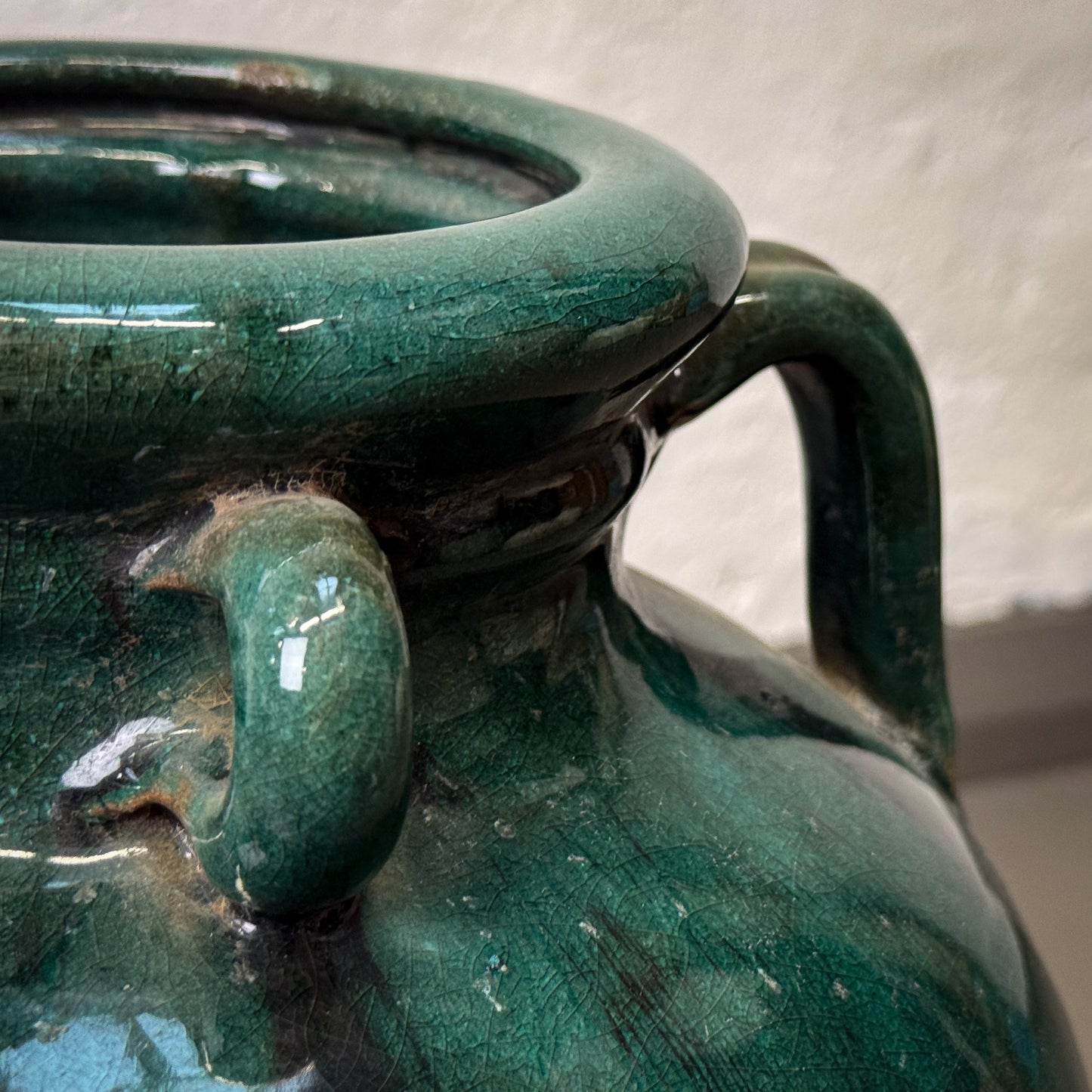 Close-up of a green ceramic vase with a textured surface.