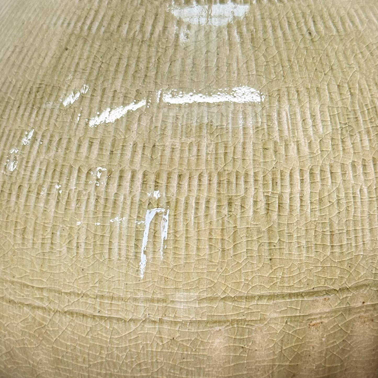 Three ceramic pots with textured surface on a wooden surface against a white wall.