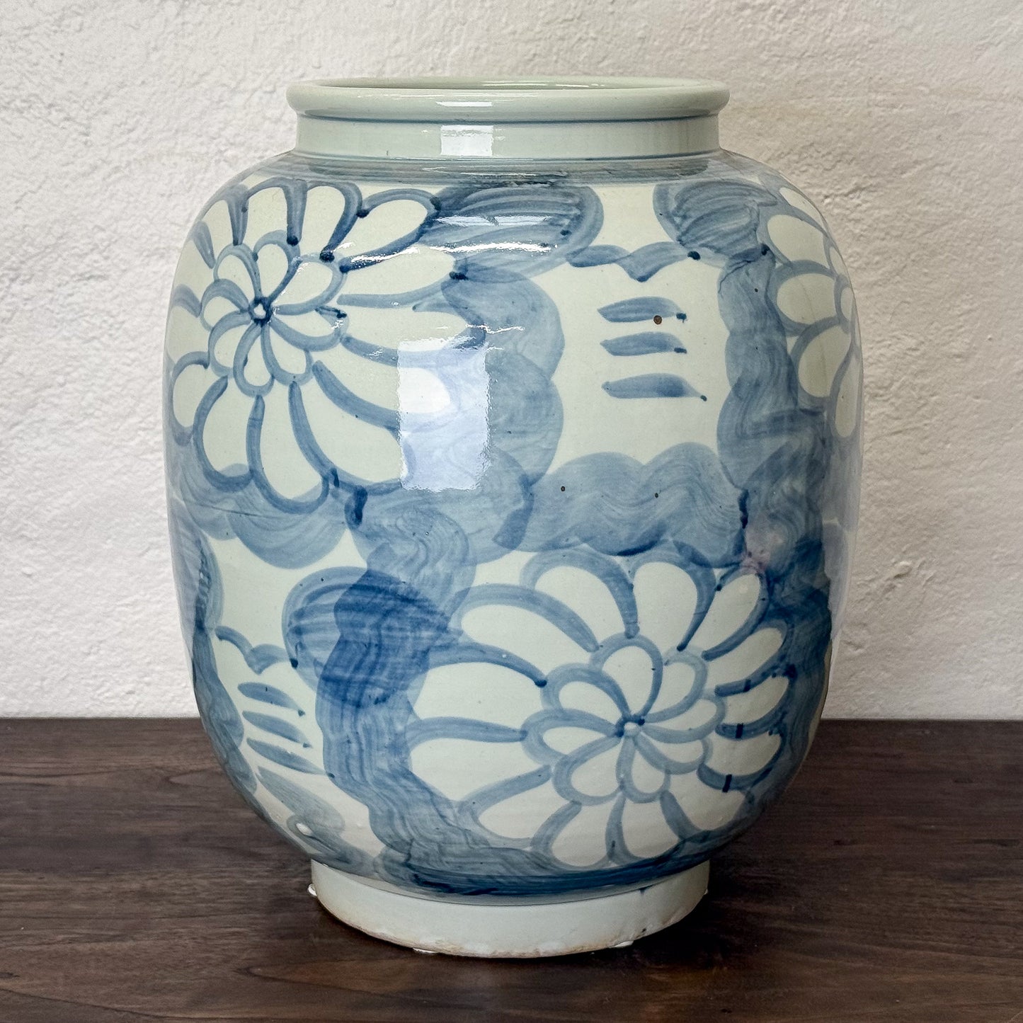 Ceramic vase with blue floral patterns on a wooden surface and white wall background