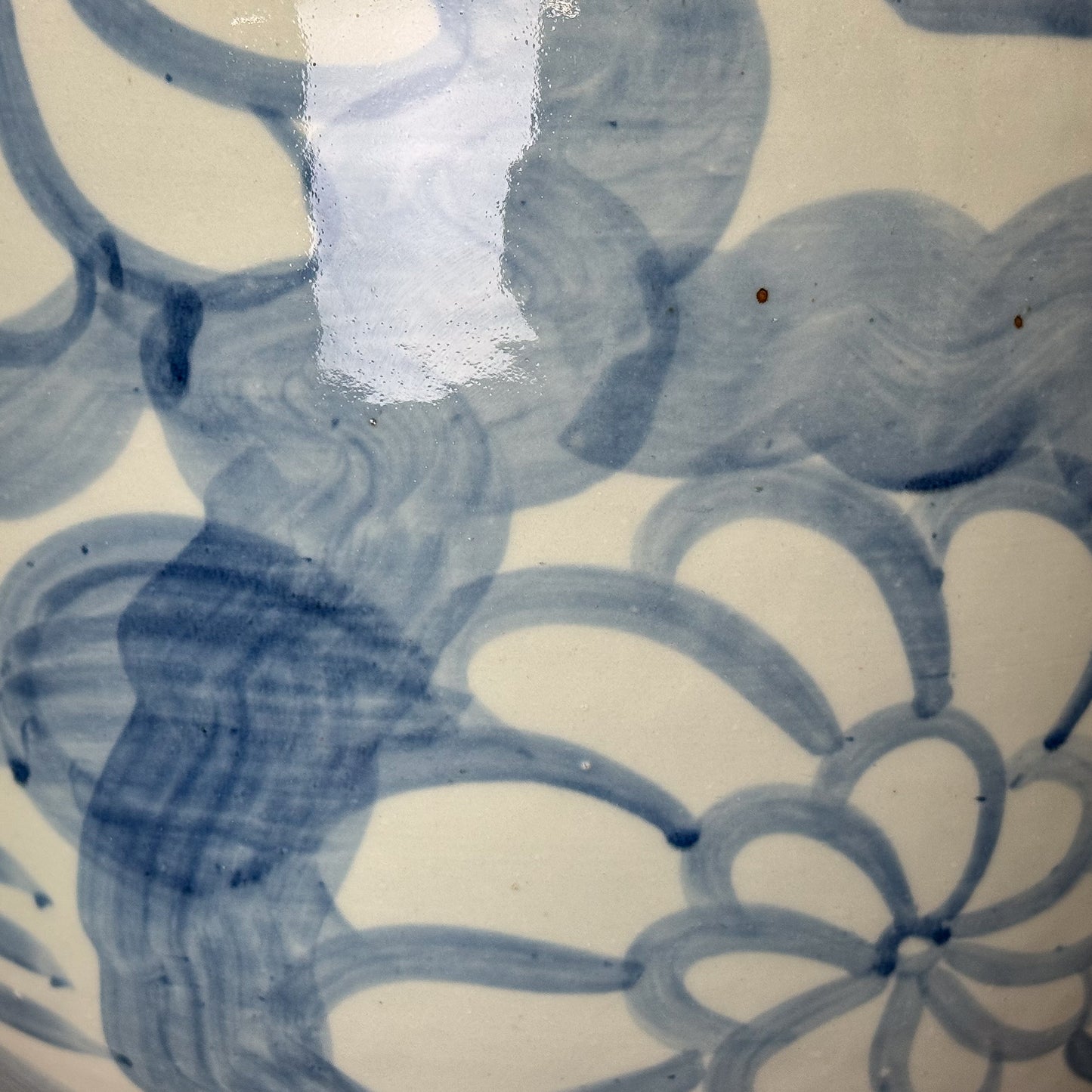 Ceramic vase with blue floral patterns on a wooden surface and white wall background