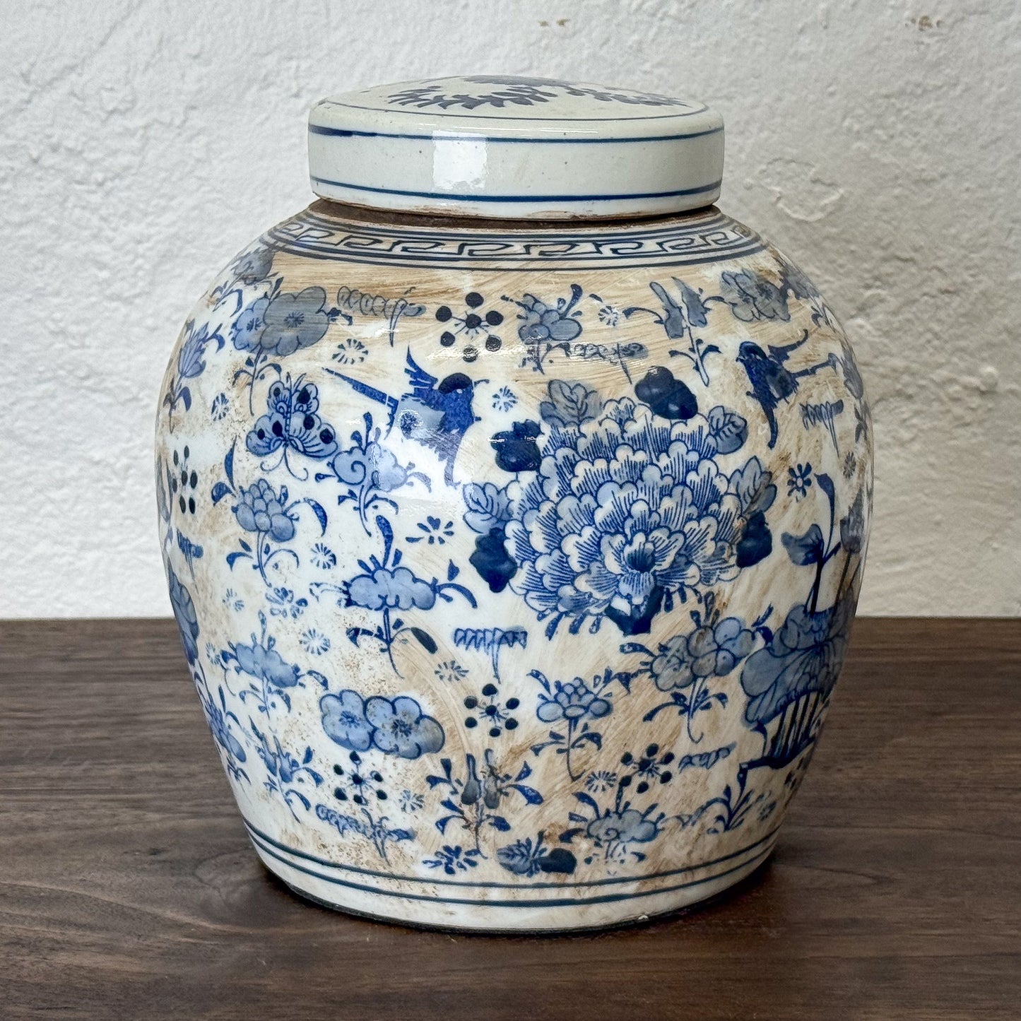 Decorative ceramic jar with blue floral patterns on a wooden surface.
