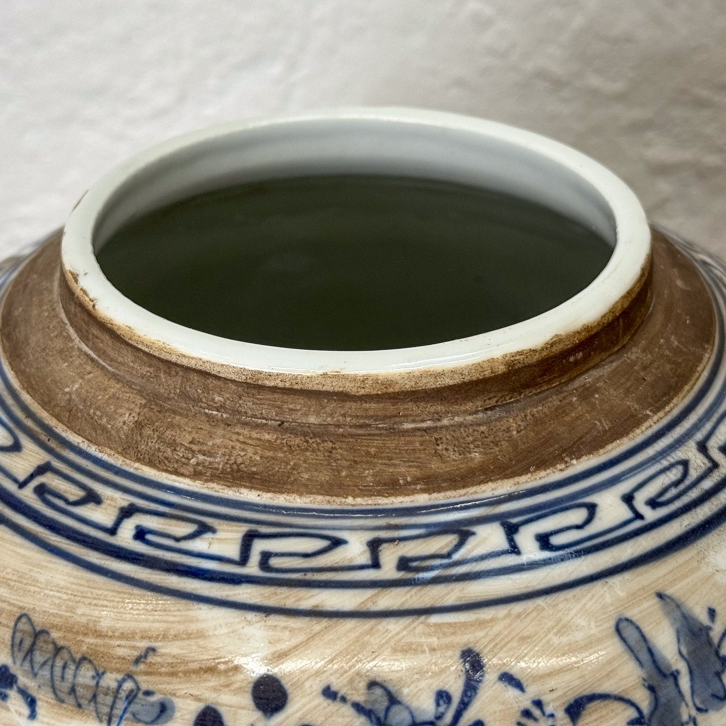 Close-up of a ceramic jar with blue and white decorative patterns on a neutral background