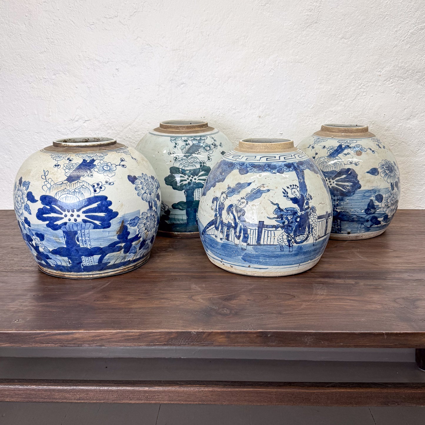Four ceramic jars with blue and white patterns on a wooden surface.