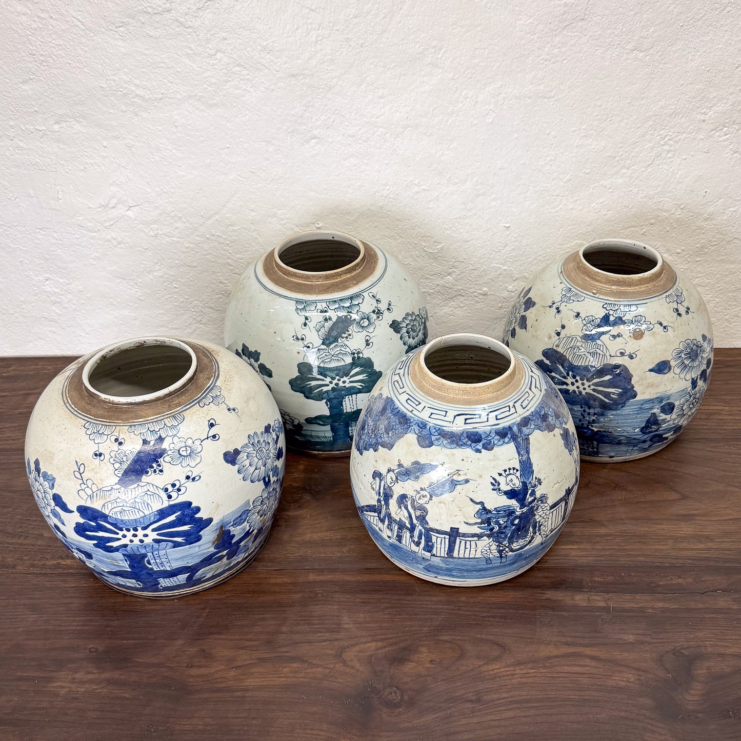 Set of four ceramic vases with blue and white floral patterns on a wooden surface.