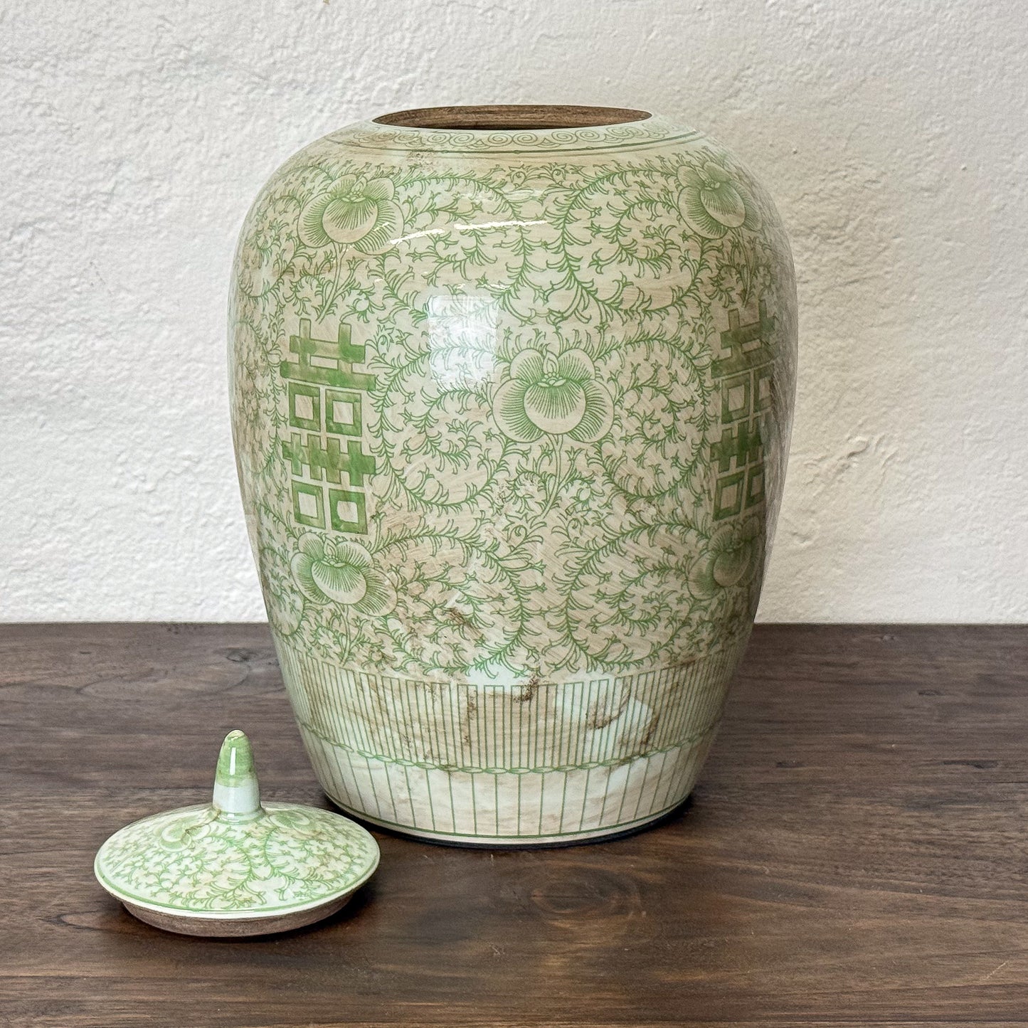 Green ceramic jar with intricate patterns on a wooden surface