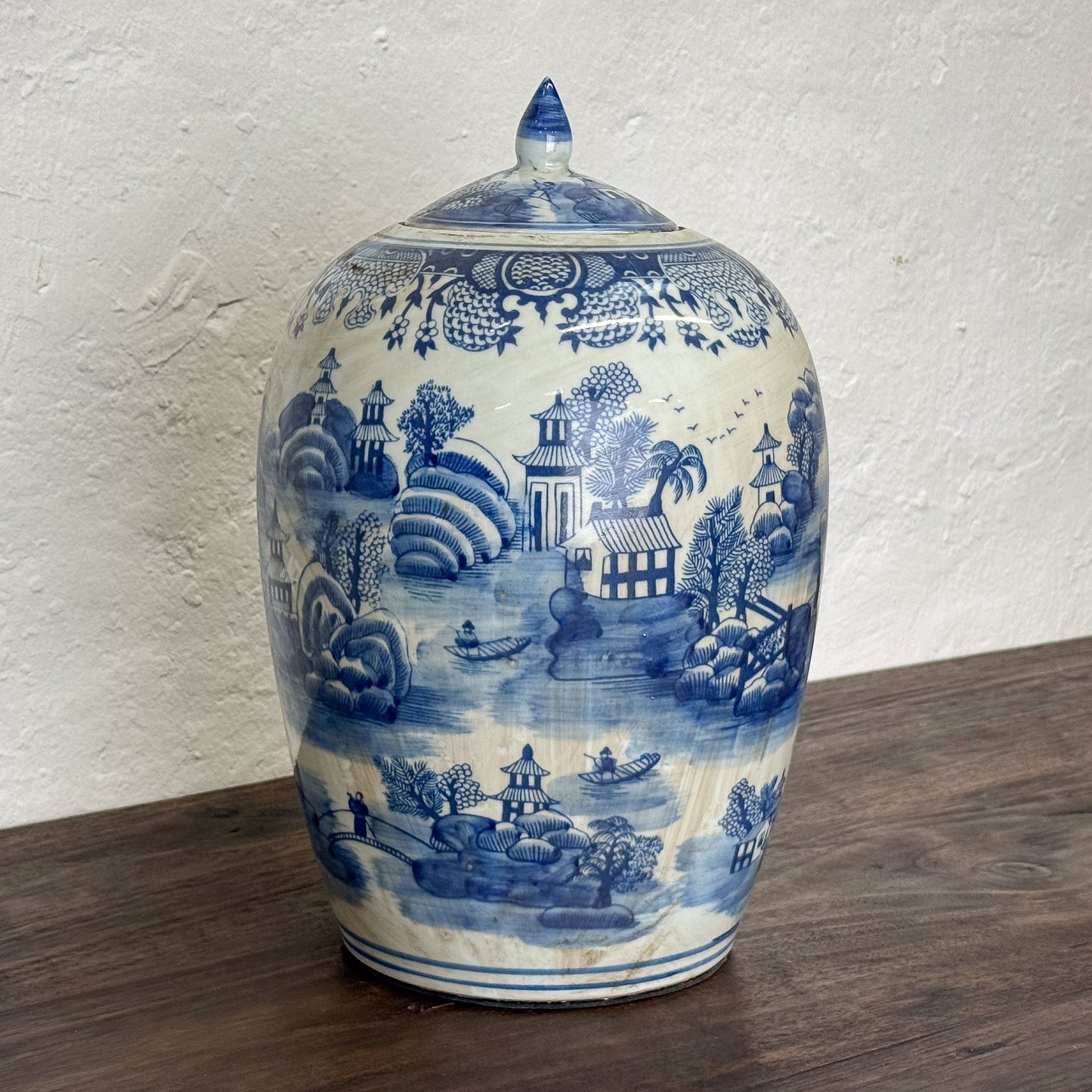 Blue and white ceramic jar with landscape design on a wooden surface