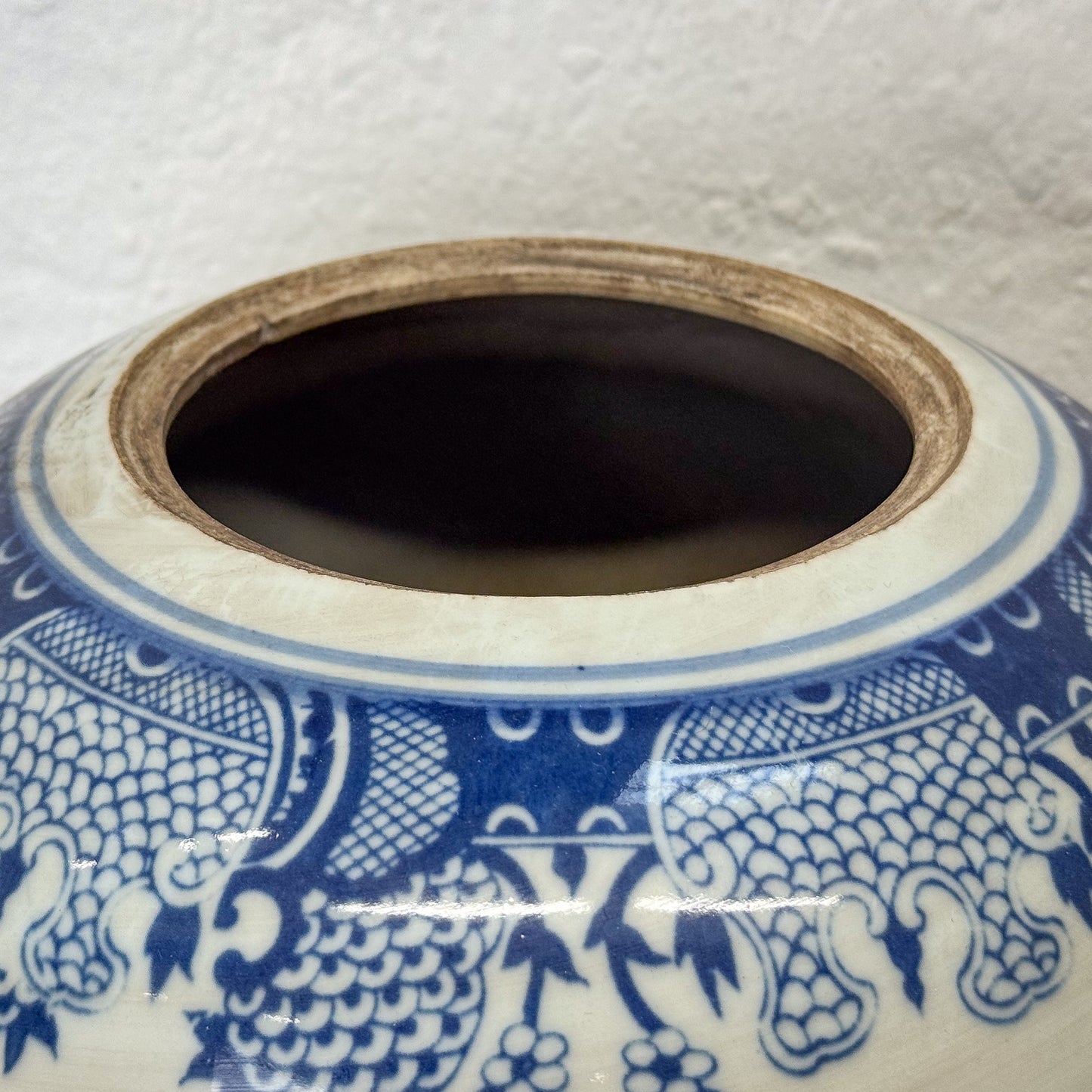 Close-up of a ceramic jar with blue and white dragon design on a textured white background