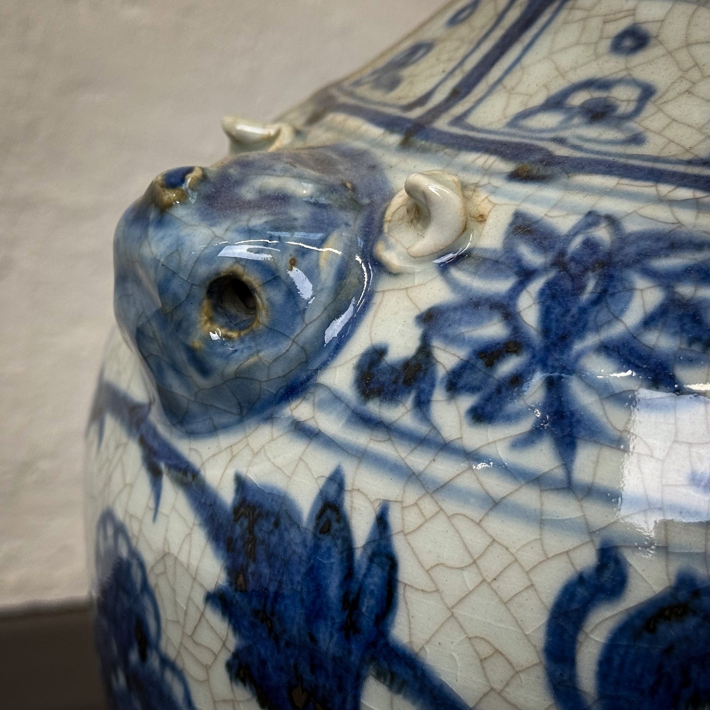 Close-up of a ceramic vase with blue floral patterns and cracked surface.
