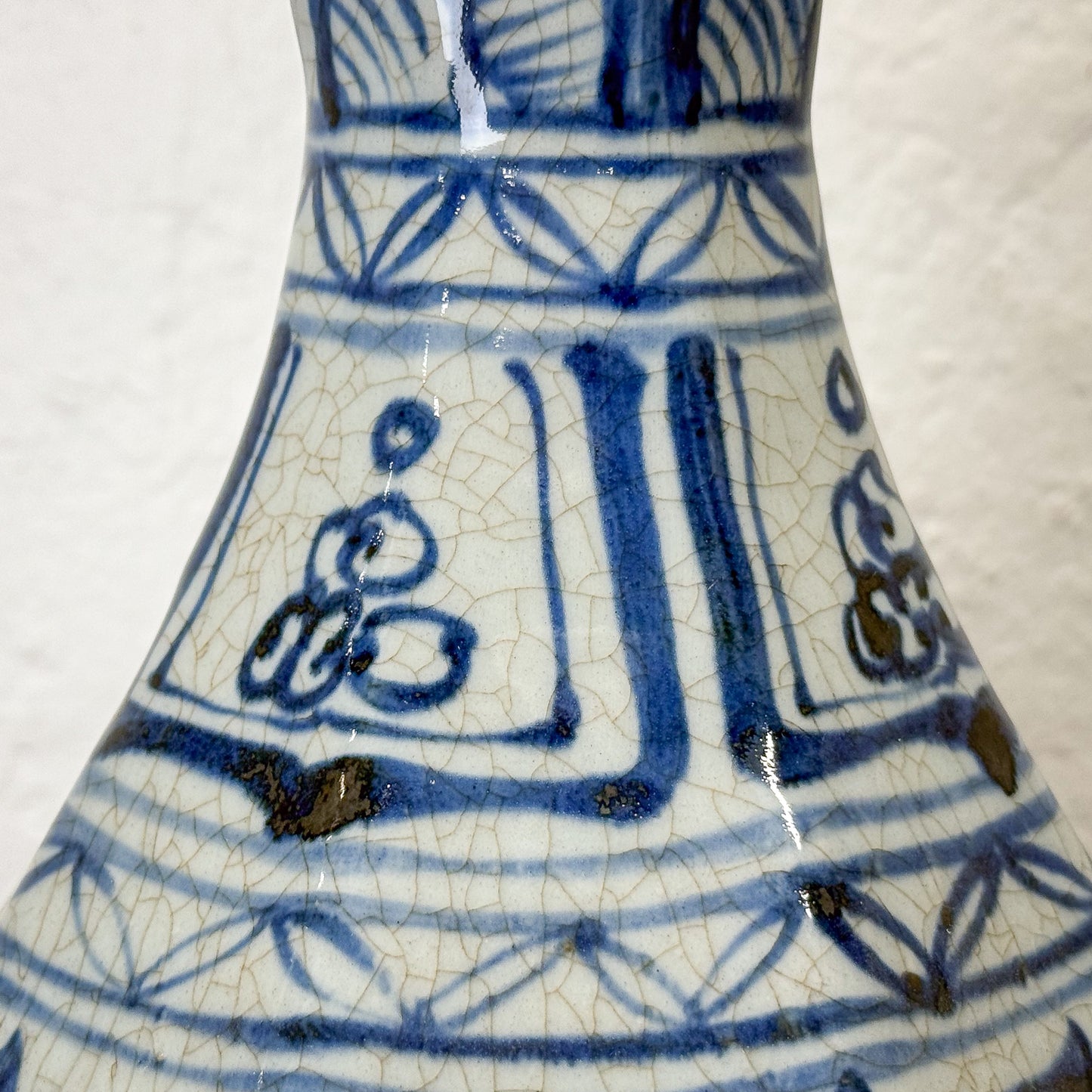 Close-up of a ceramic vase with blue and white geometric patterns on a white background