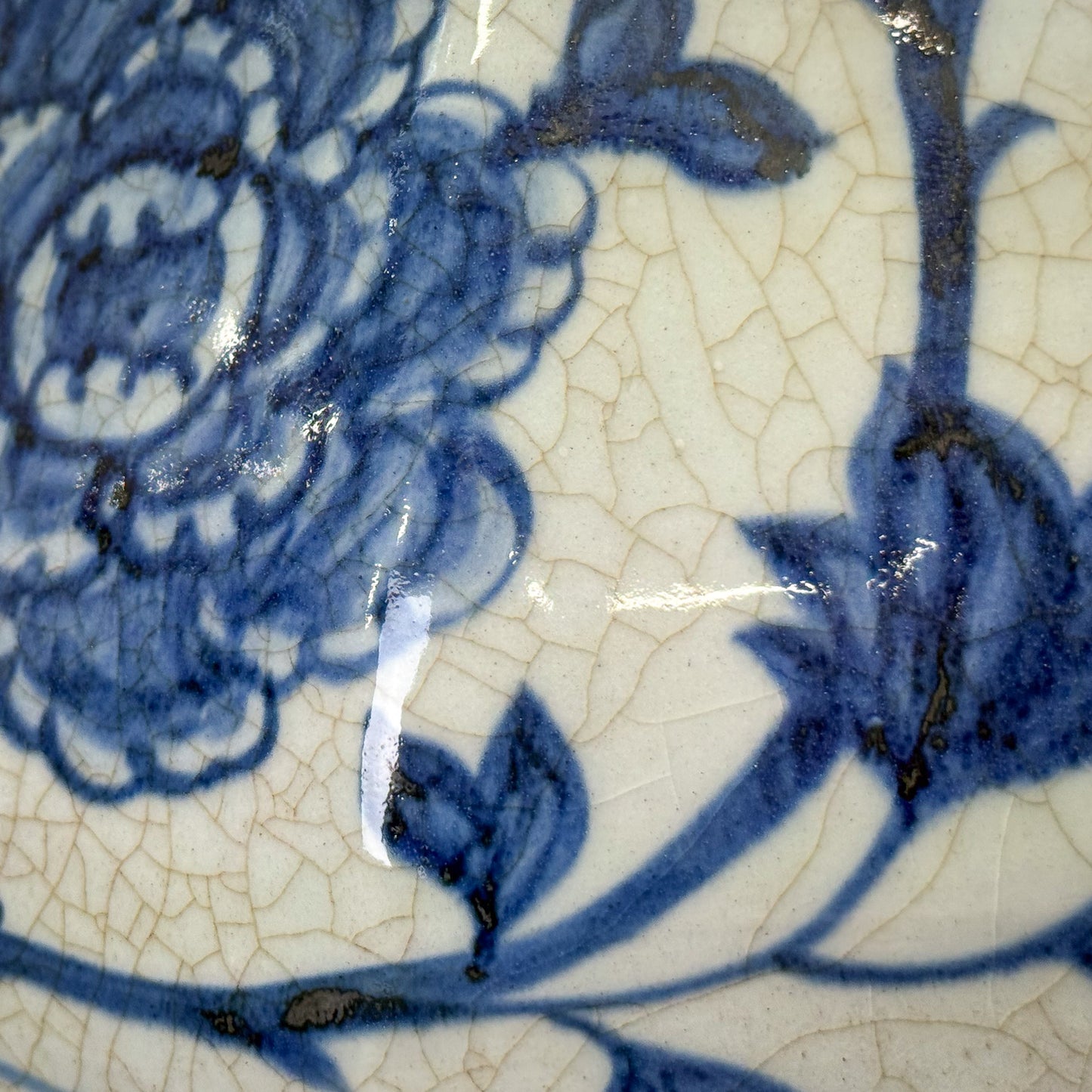 Close-up of blue floral design on a ceramic surface with visible cracks.