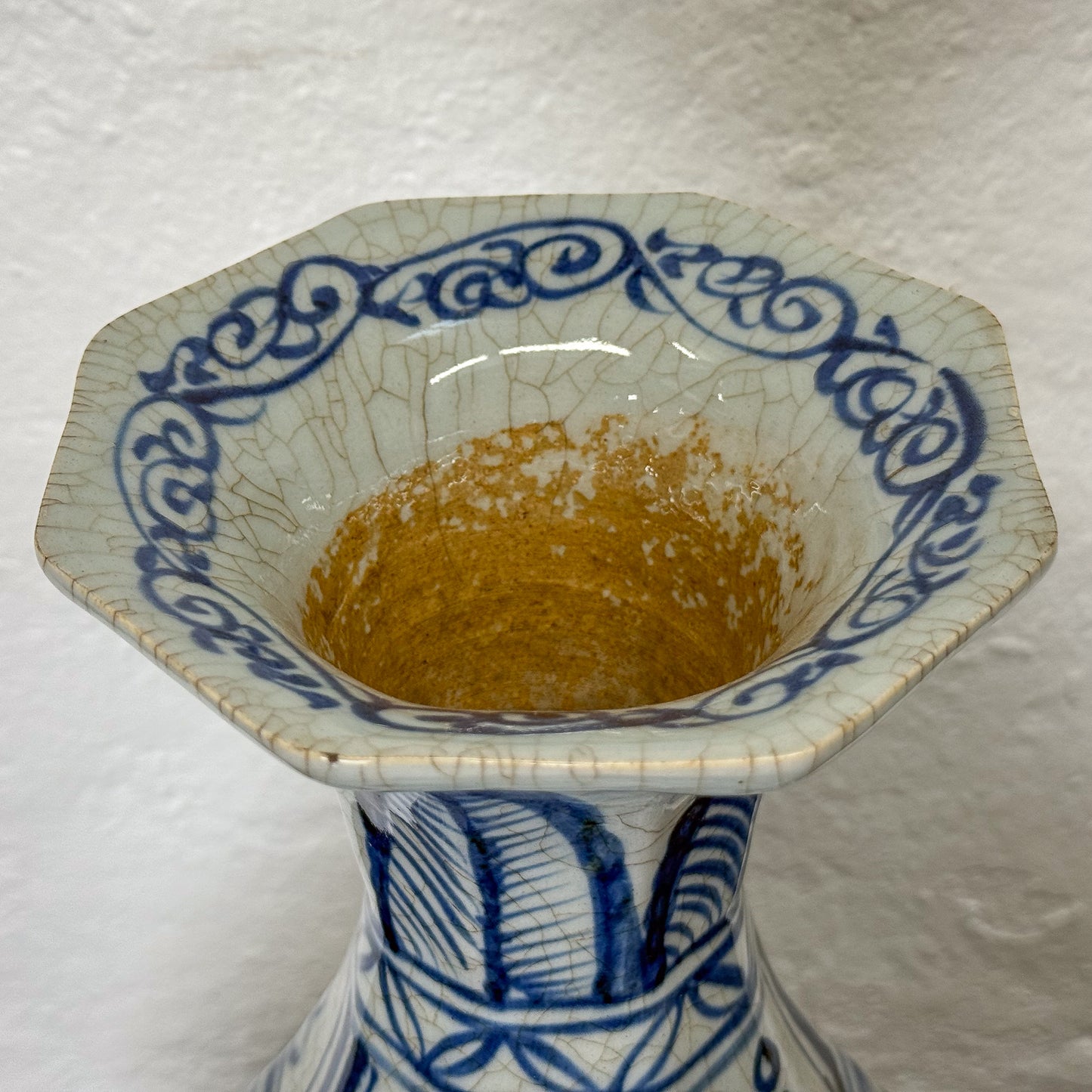 Blue and white ceramic vase with cracked glaze on a textured white background