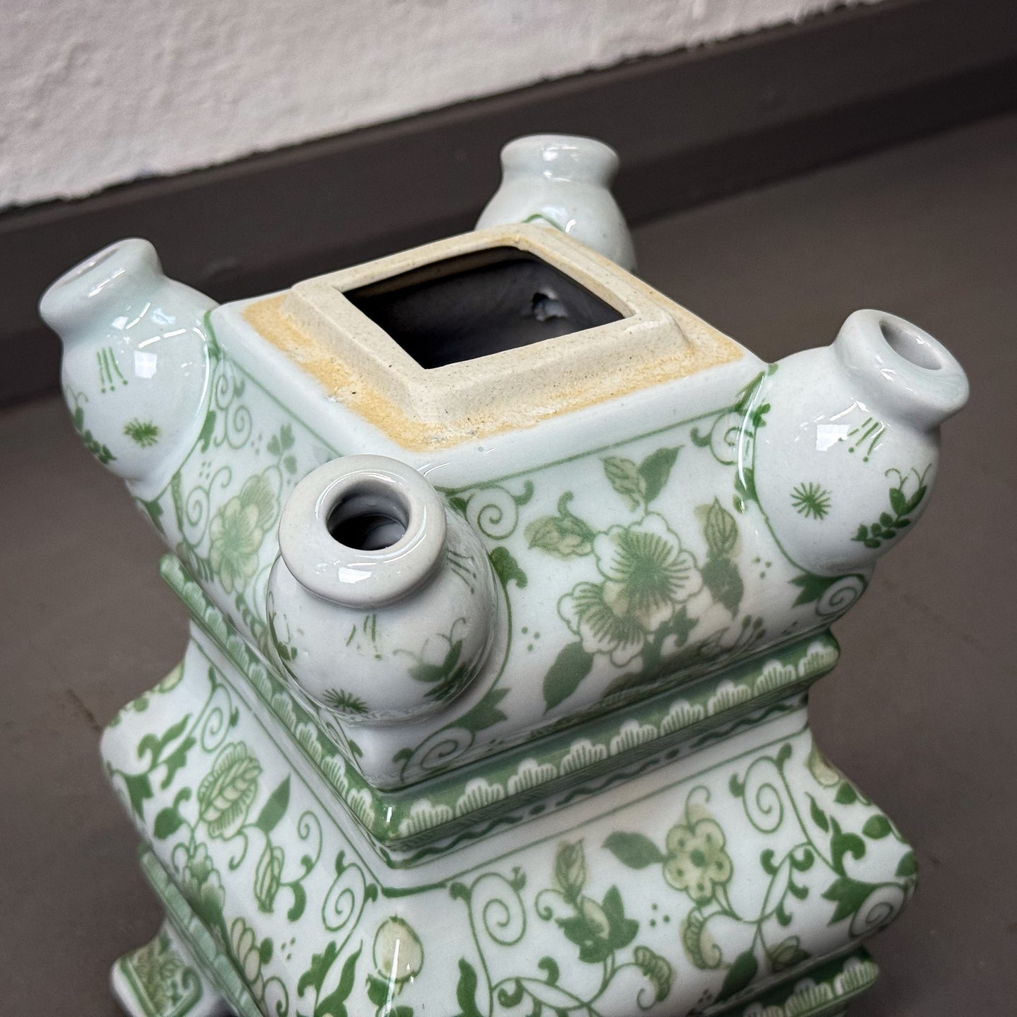 Ceramic pot with green floral patterns on a neutral background