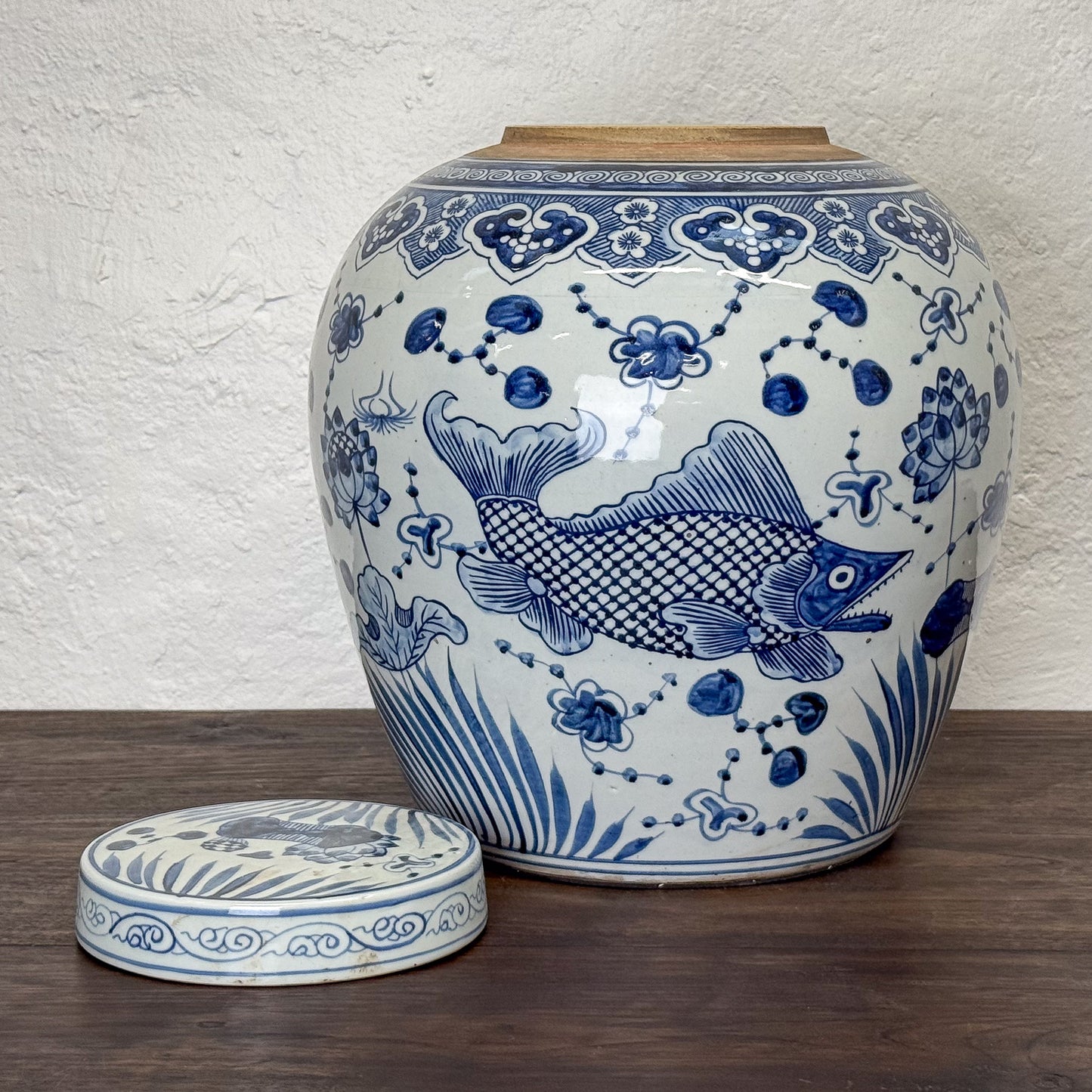 Blue and white ceramic jar with fish design on a wooden surface