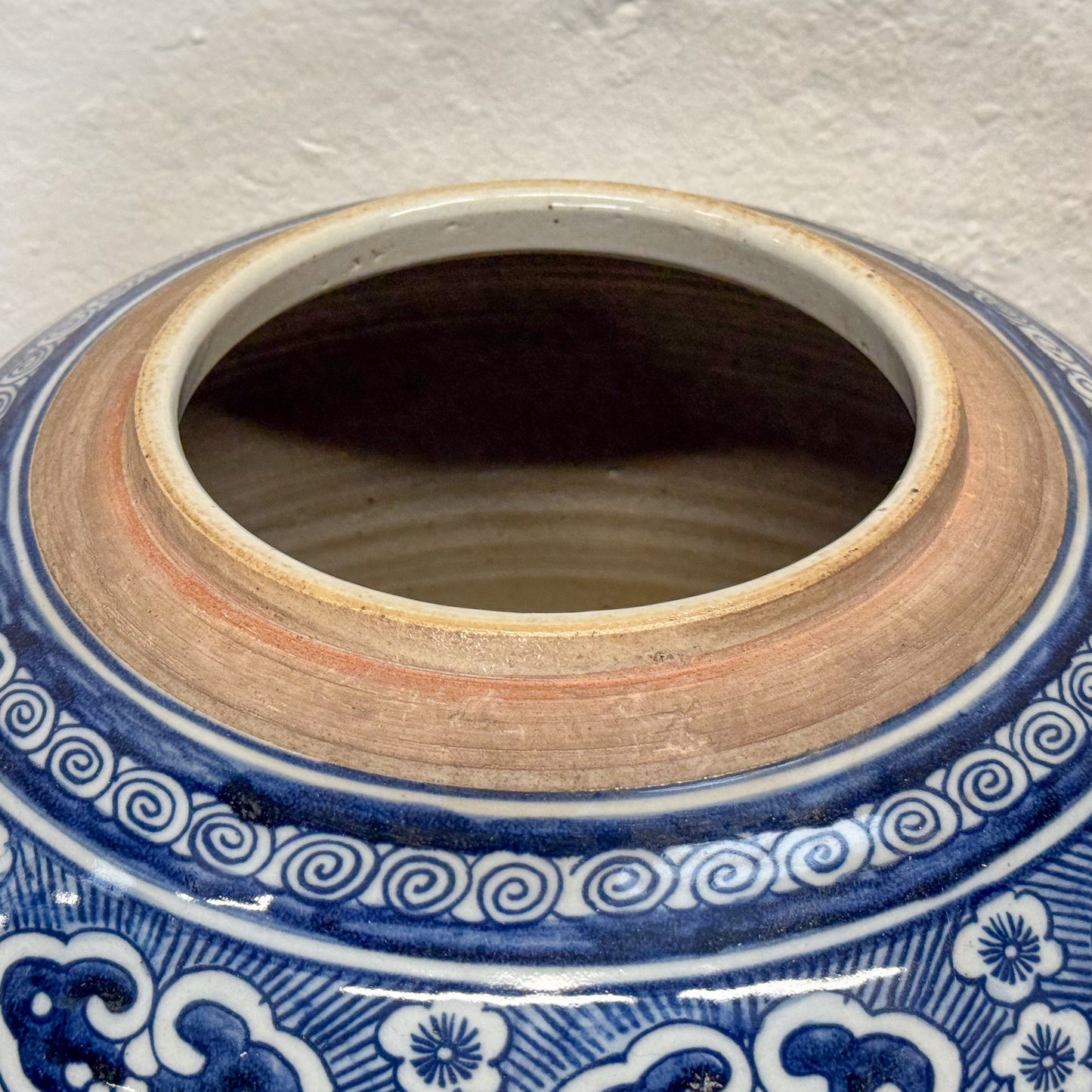 Close-up of a ceramic jar with blue and white decorative patterns on a textured surface.