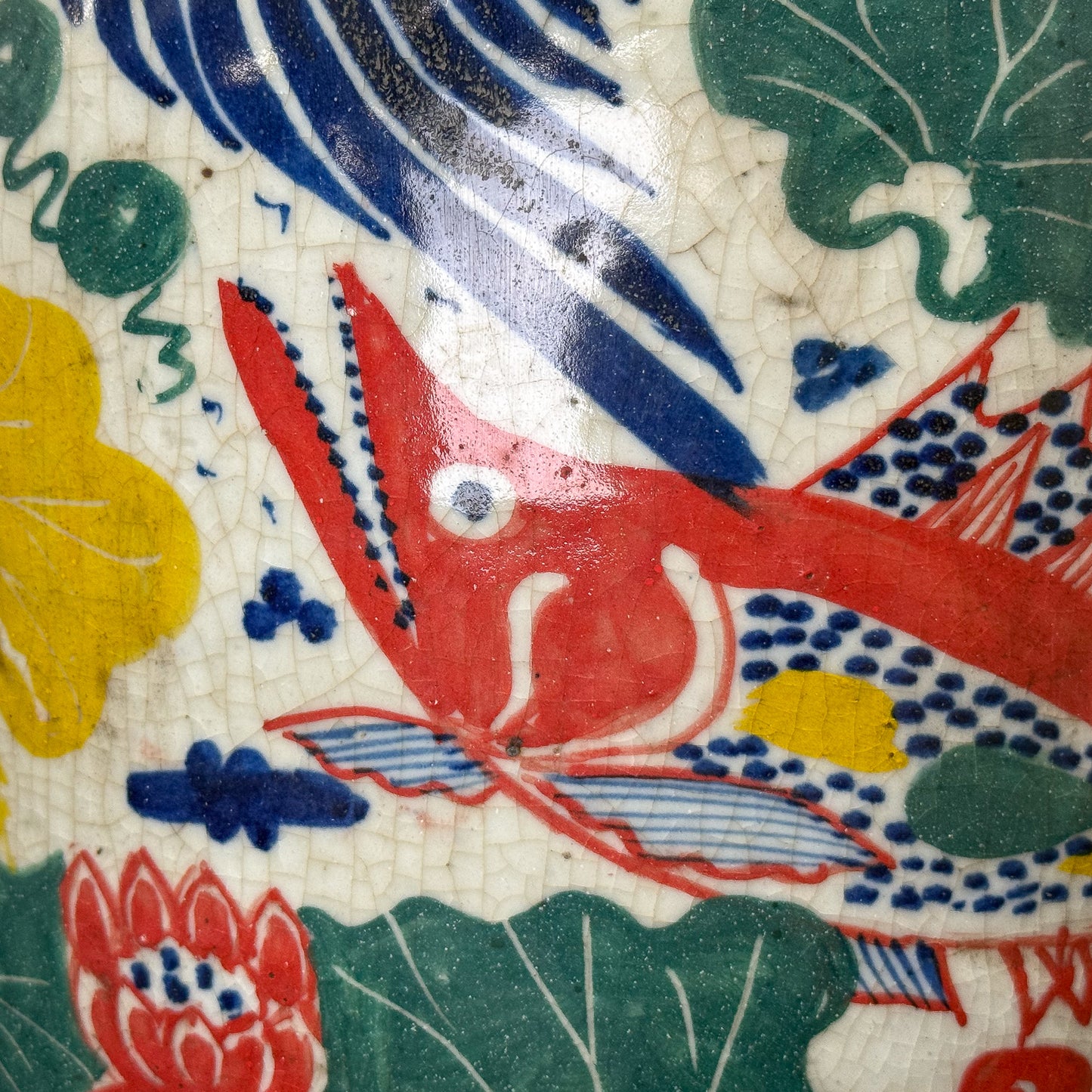 Colorful ceramic tile with a red fish and floral patterns
