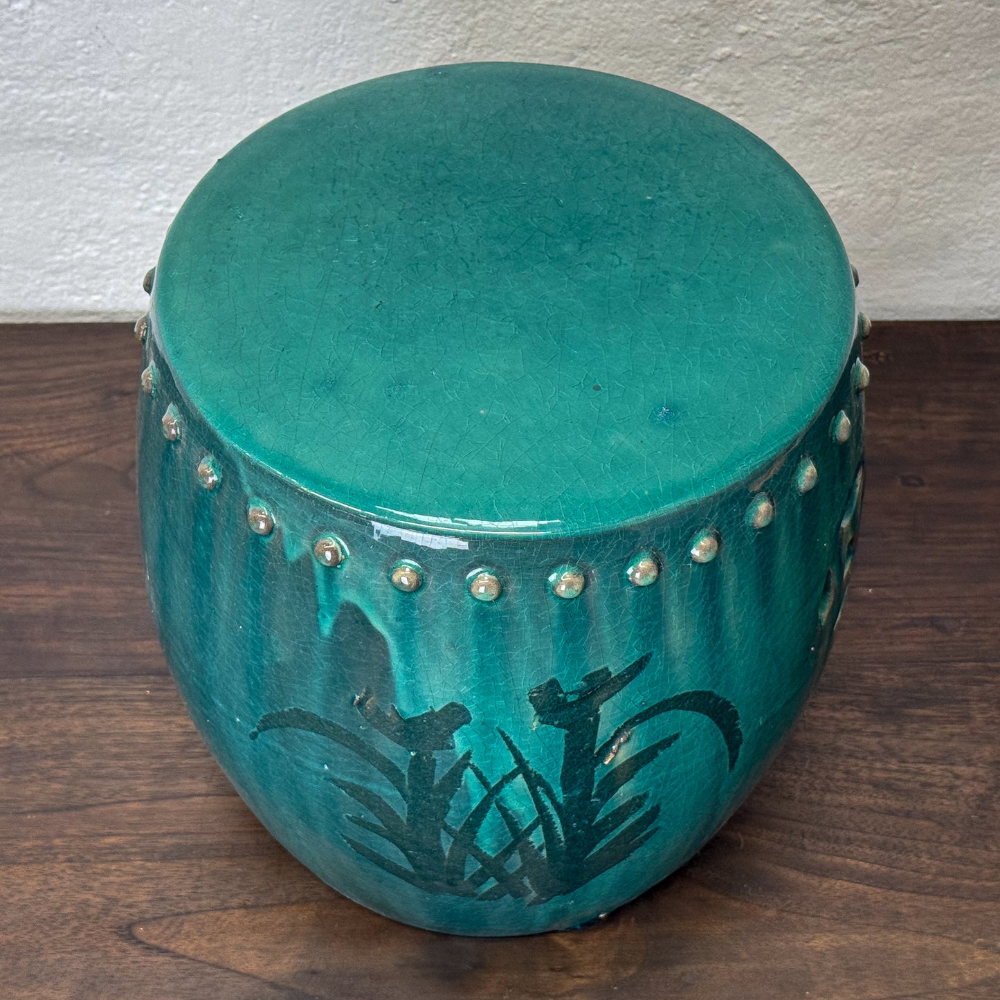 Turquoise drum with decorative elements on a wooden floor