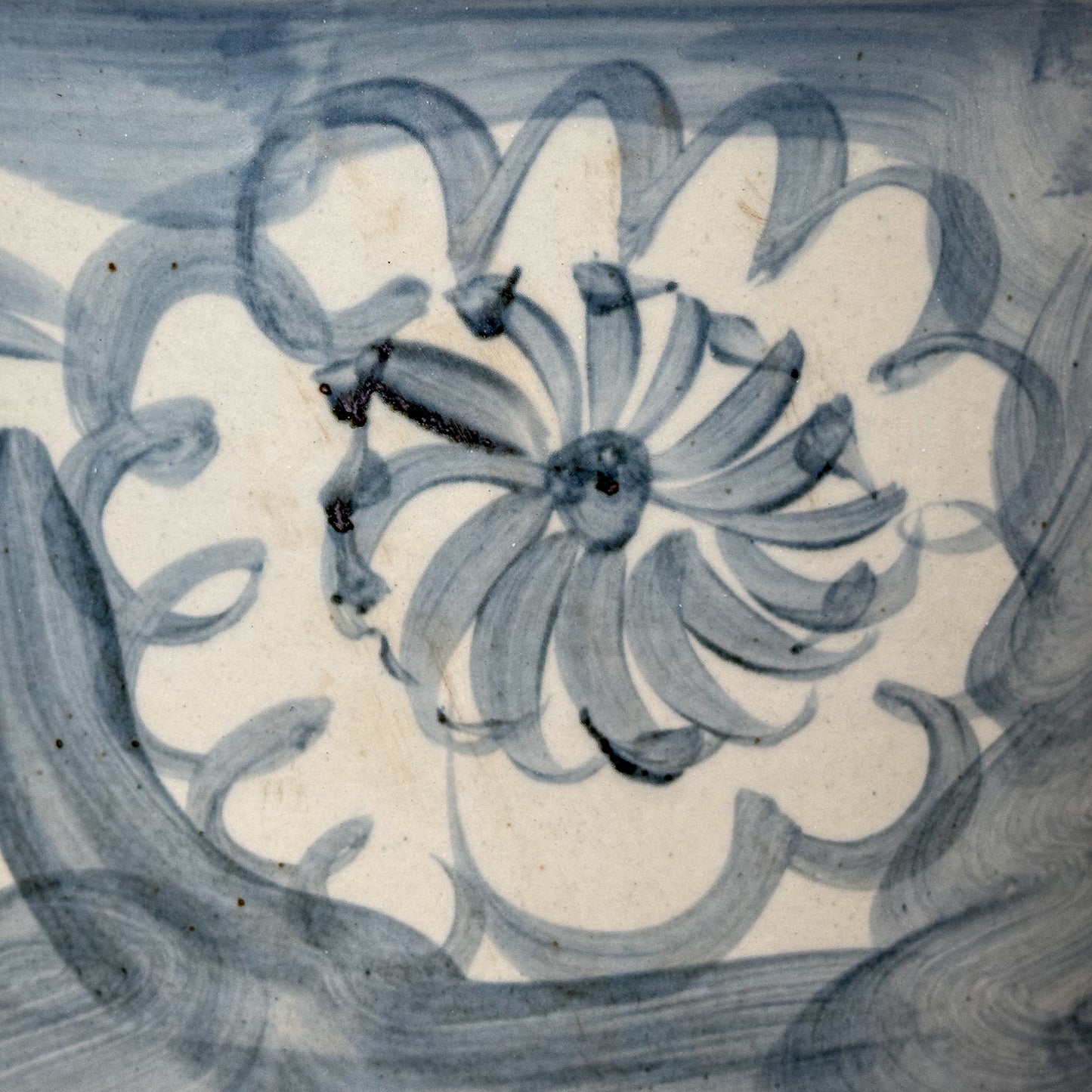 Decorative tile with floral design in blue on a beige background