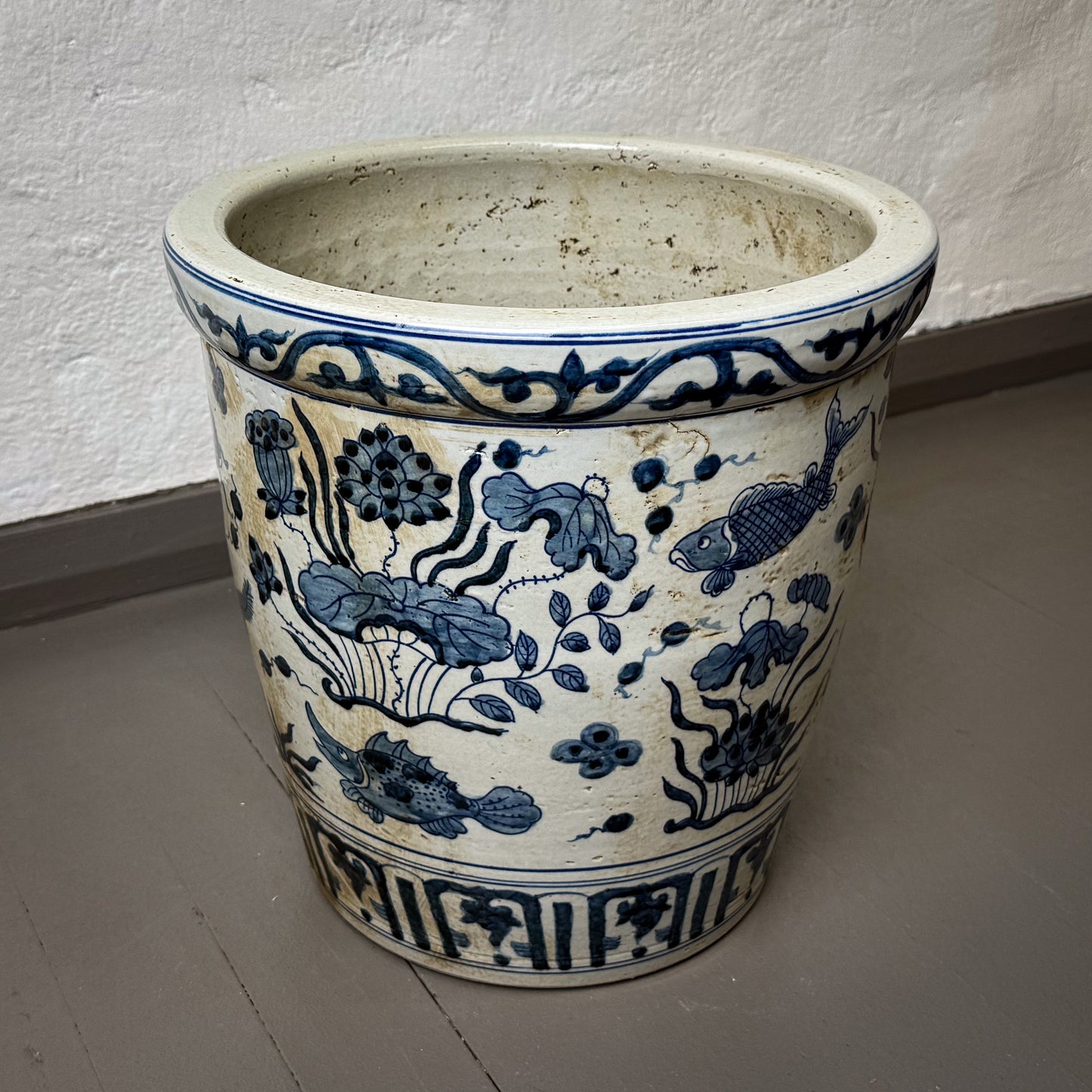Ceramic pot with blue floral and fish design on a plain background