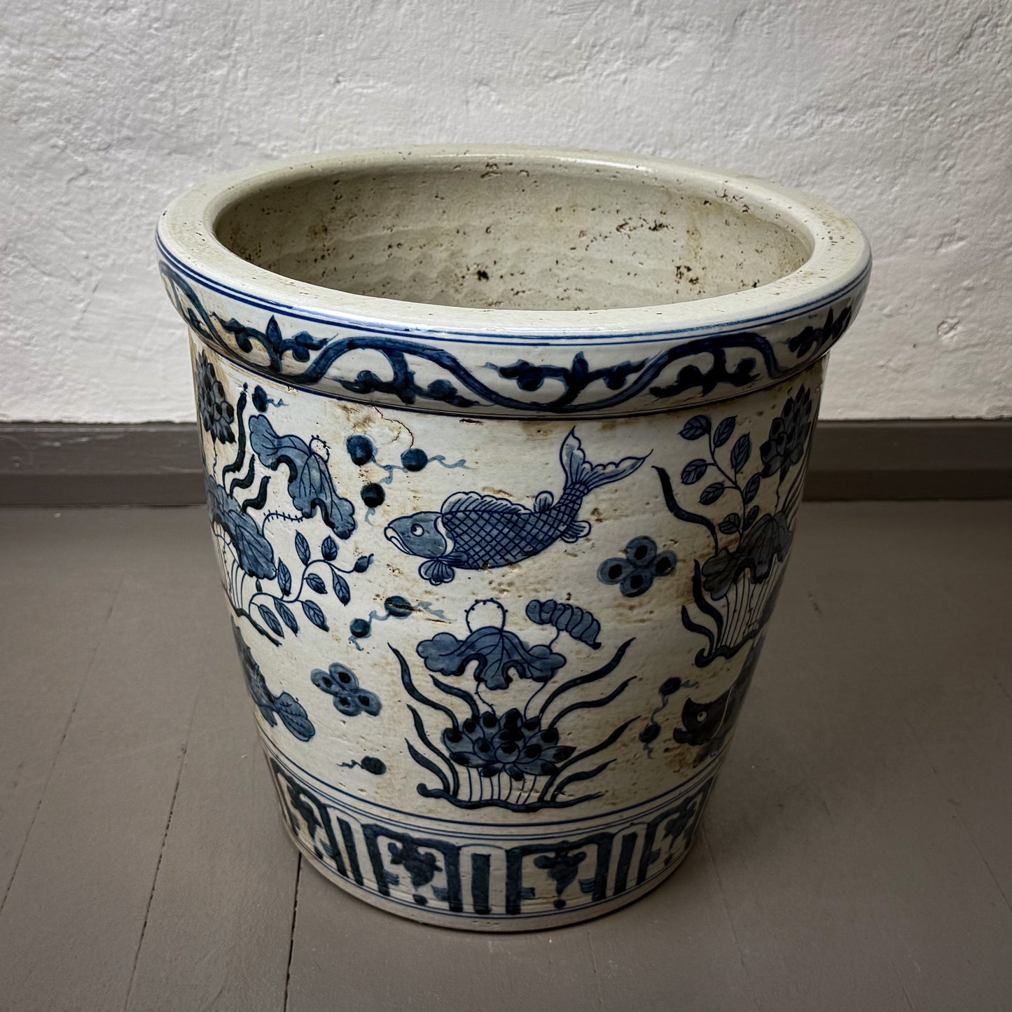 Ceramic pot with blue floral and fish design on a plain background