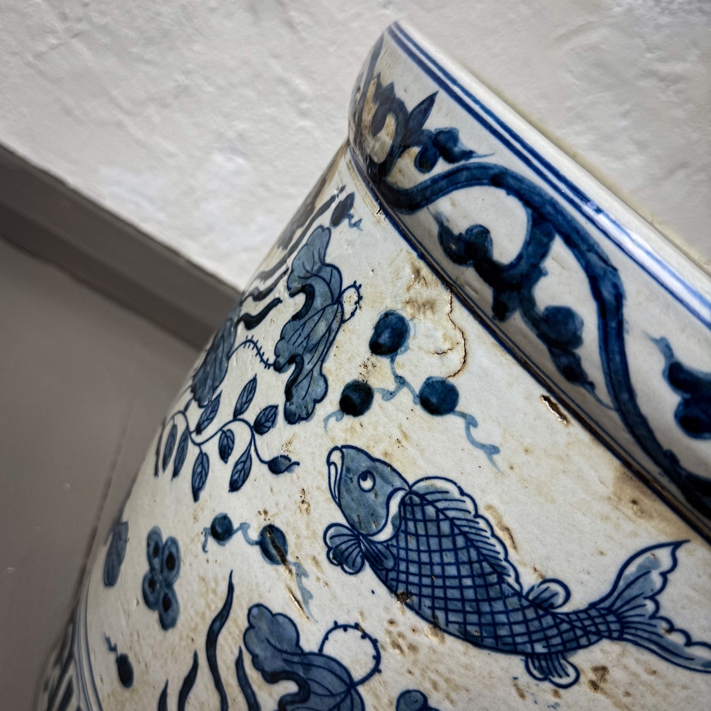 Ceramic vase with blue floral and fish patterns on a white background