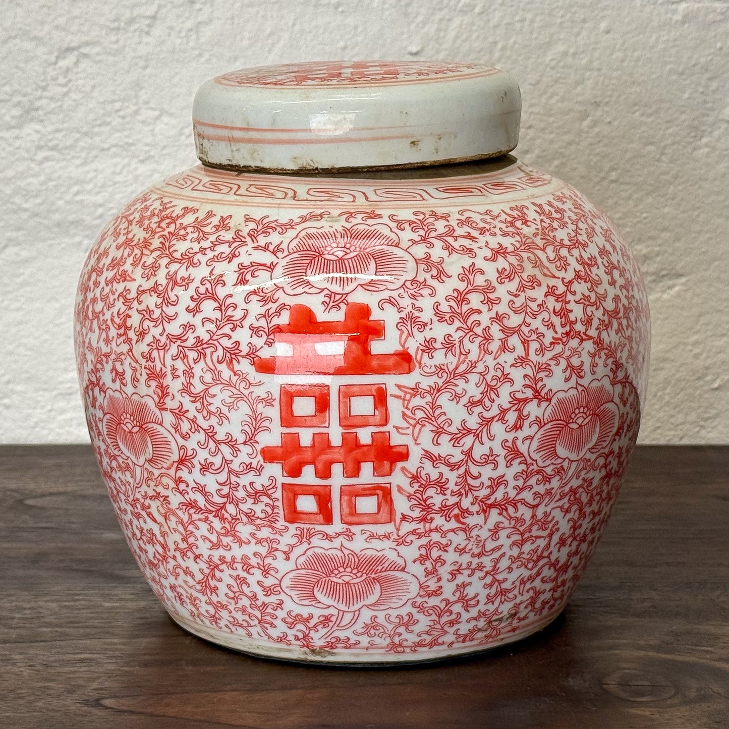 Ceramic jar with red floral patterns on a white background