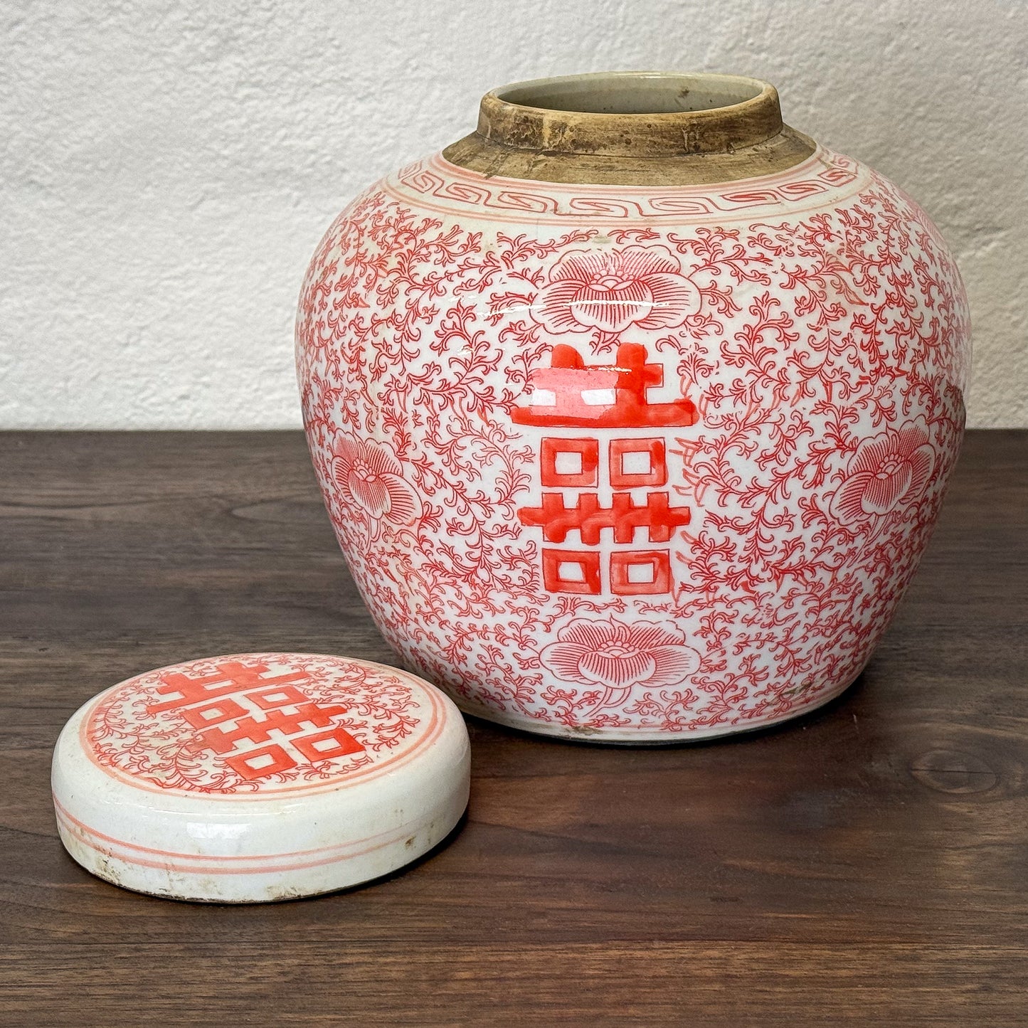 Ceramic jar with red floral patterns on a white background