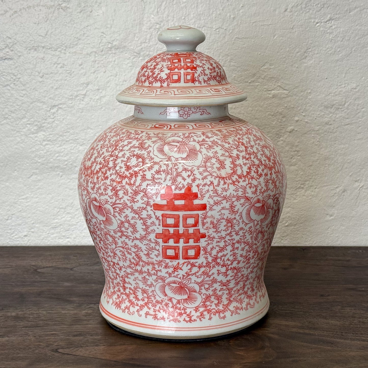 Ceramic jar with red floral patterns on a white background