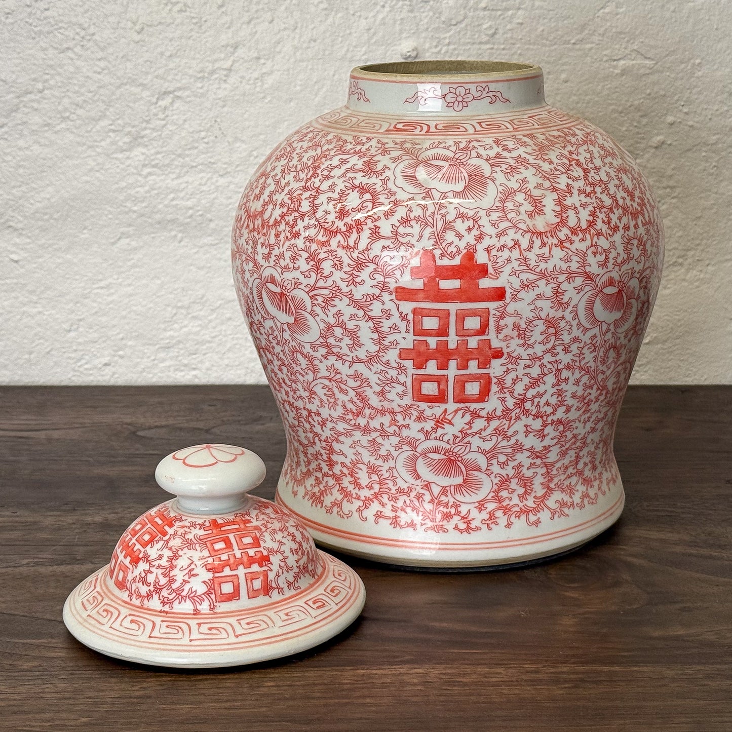 Ceramic jar with red floral patterns on a white background