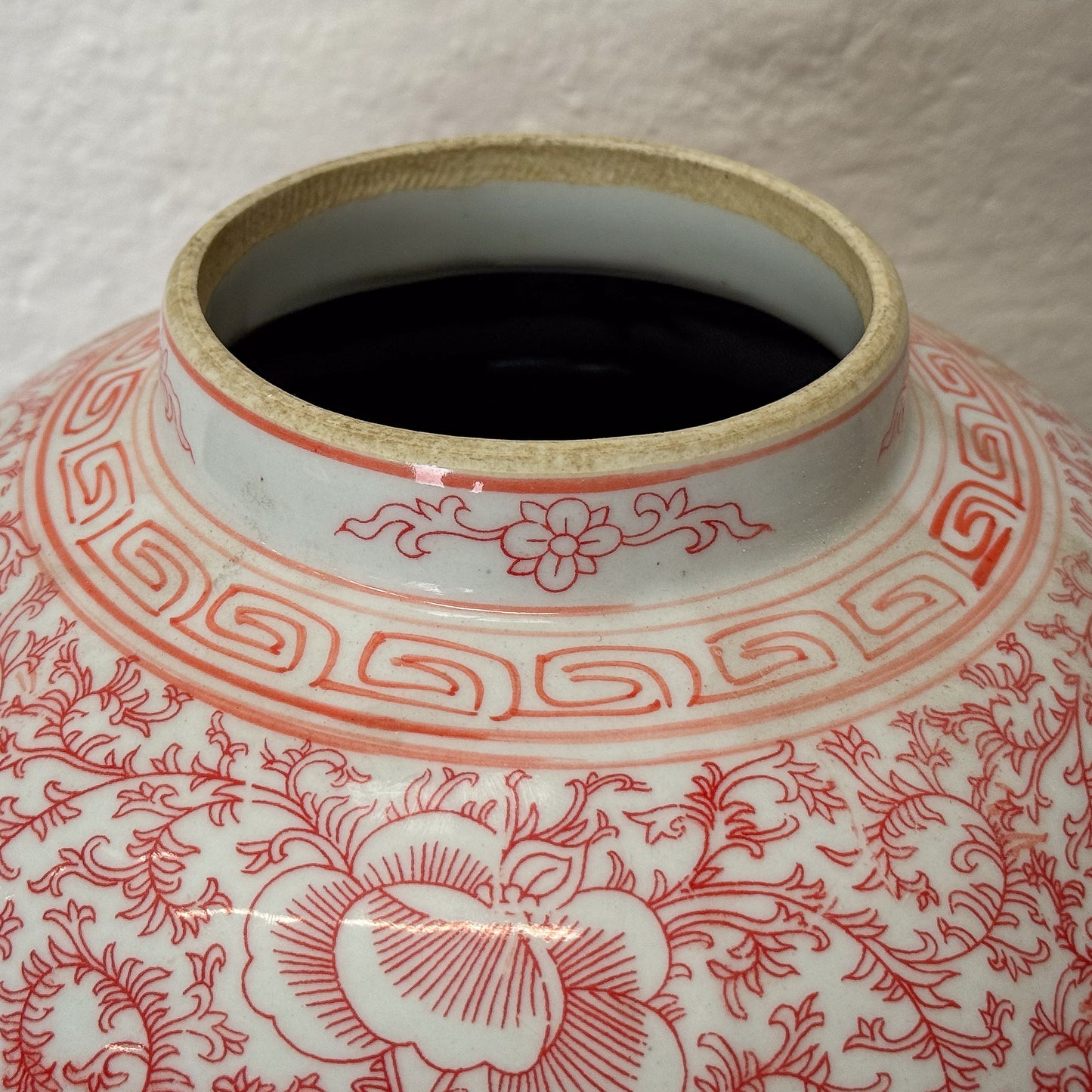 Ceramic jar with red floral patterns on a white background