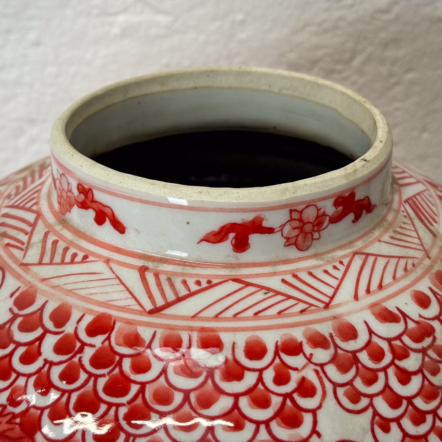 Red and white ceramic jar with phoenix design on a wooden surface.