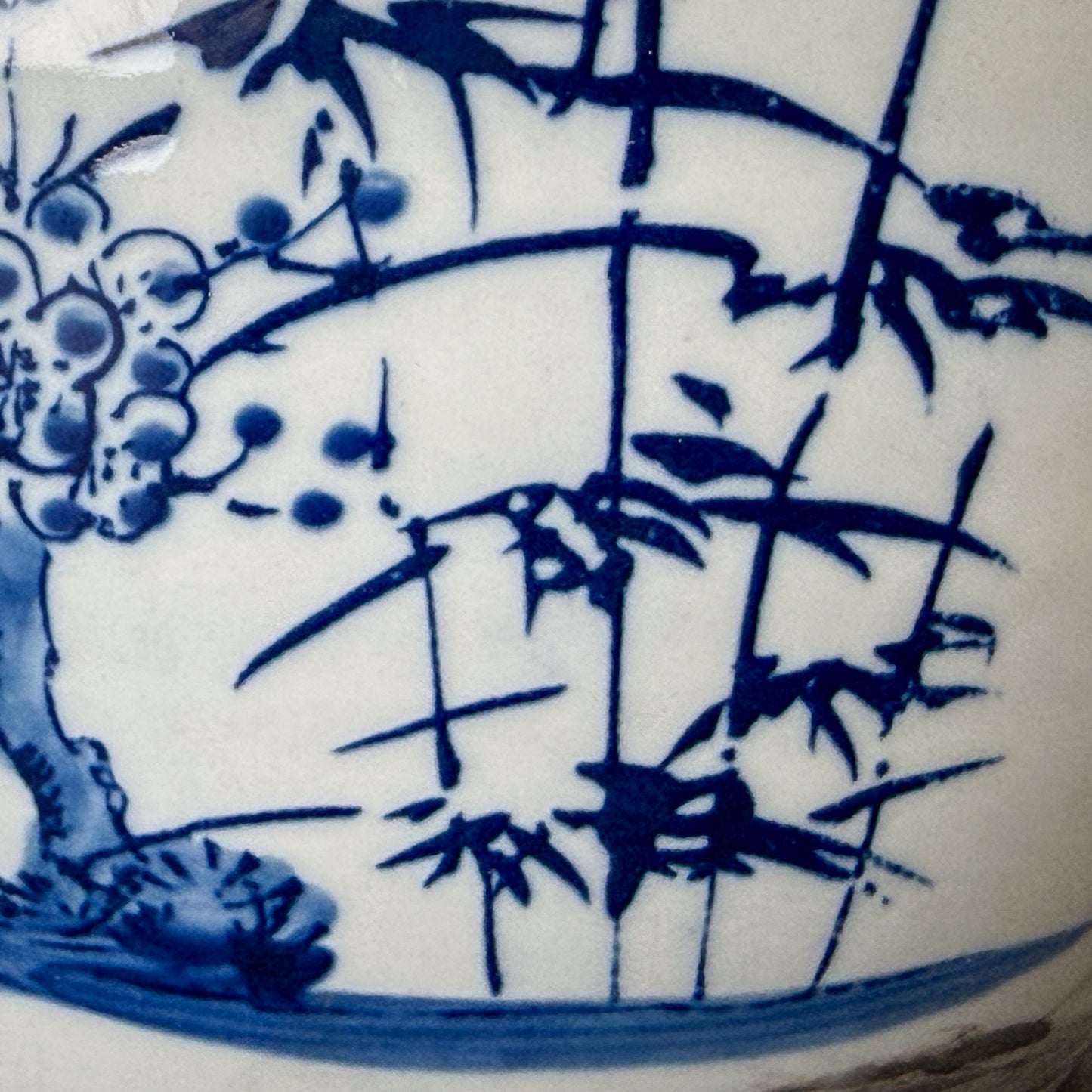 Close-up of a blue and white ceramic vase with bamboo and floral design.