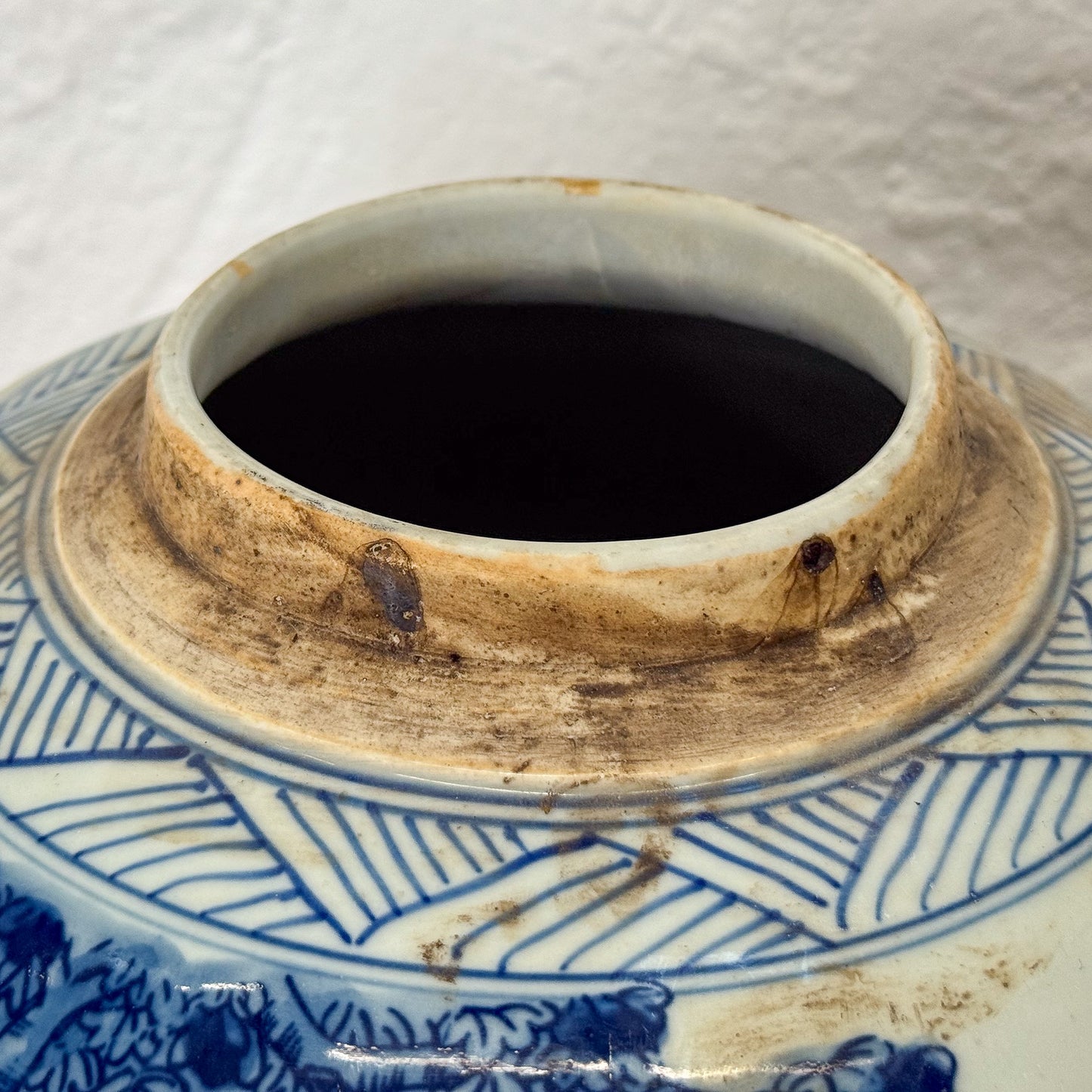 Close-up of a ceramic jar with blue and white patterns and a worn lid.