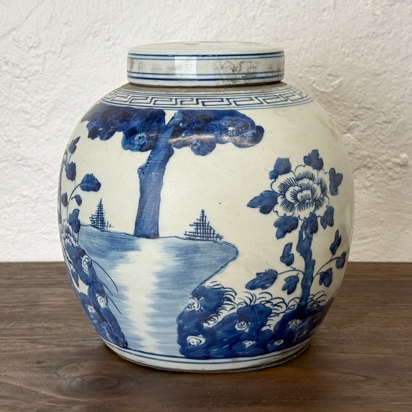 Blue and white ceramic jar with artistic designs on a wooden surface