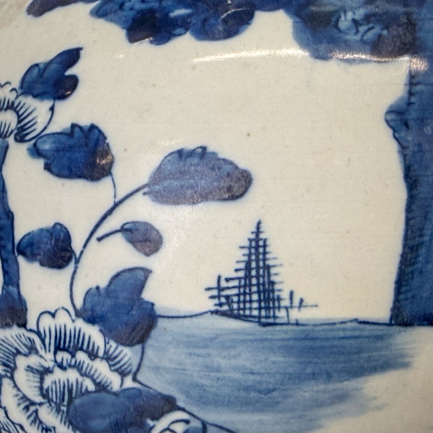 Close-up of blue floral and landscape design on white ceramic tile