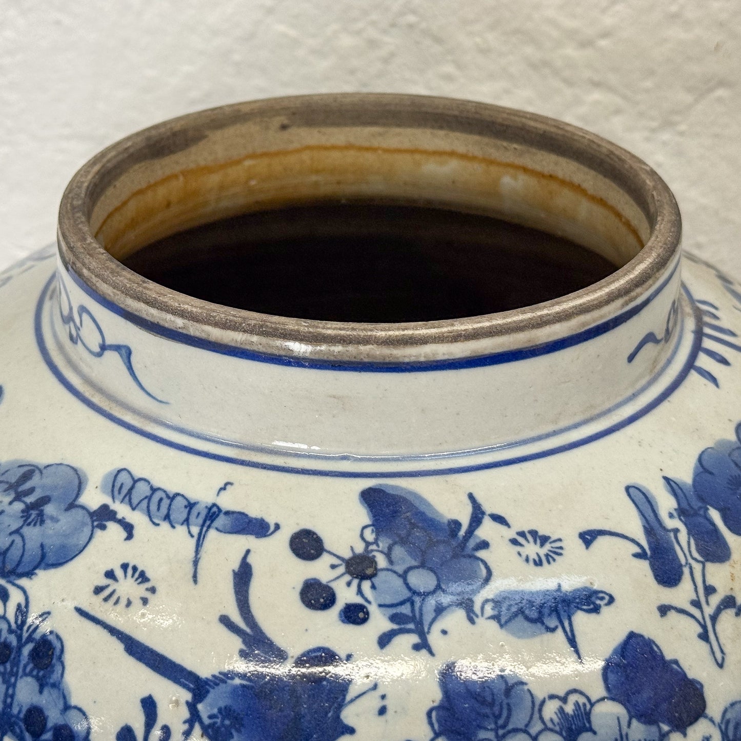 Close-up of a blue and white ceramic jar with floral patterns on a textured white background.