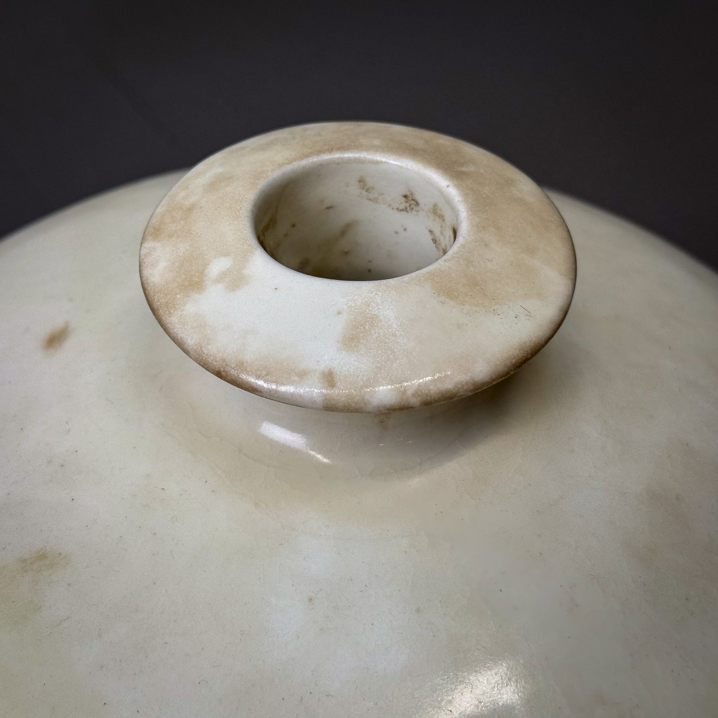 Close-up of a ceramic pot with a lid on a dark background