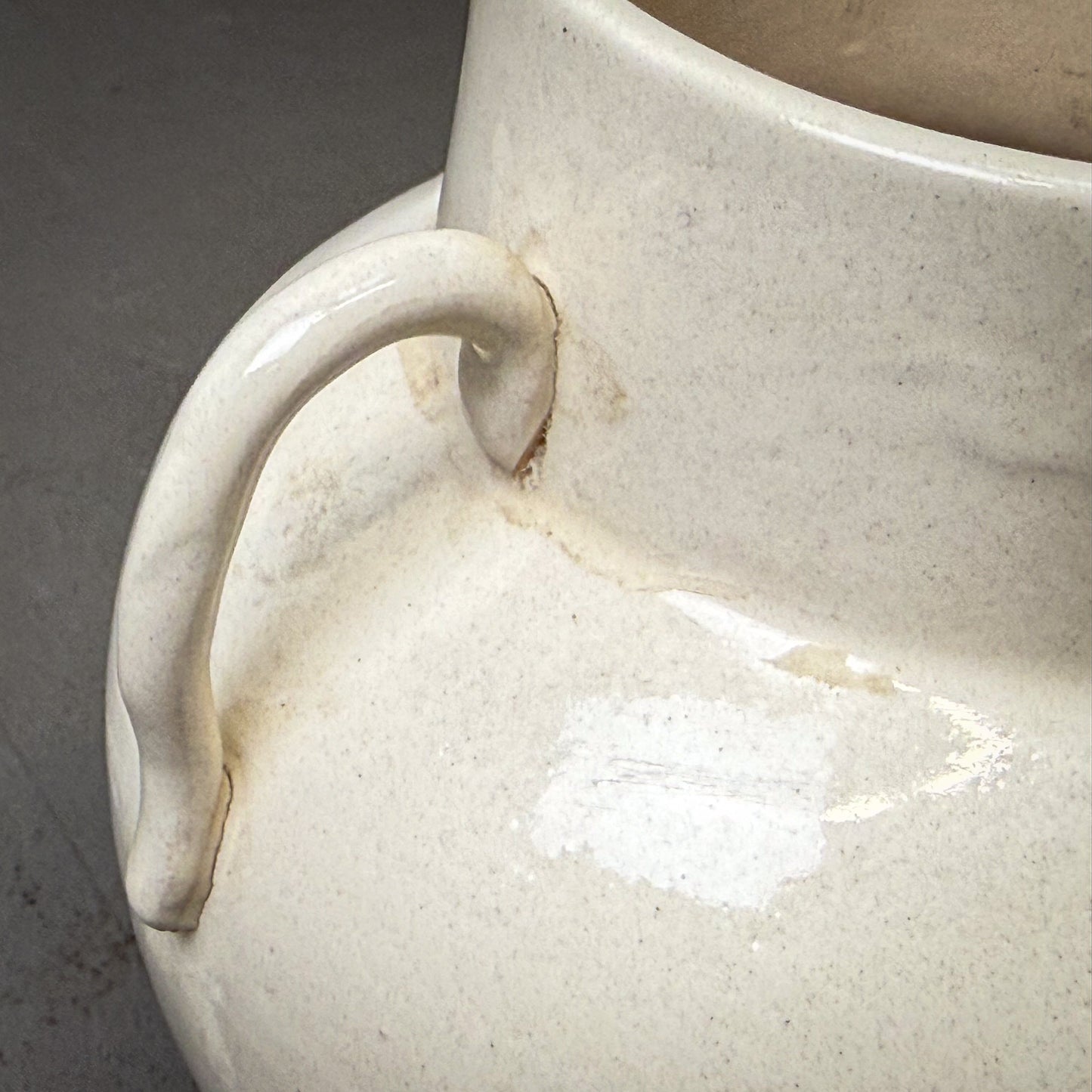 Close-up of a ceramic vase with a handle on a gray background