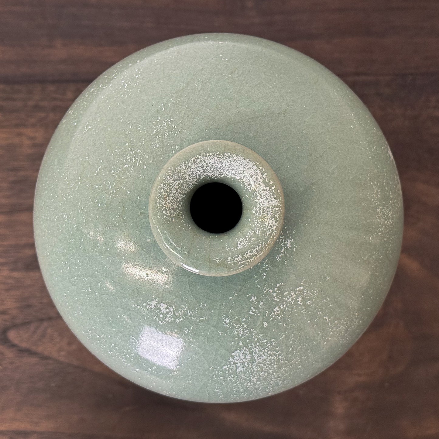 Green glass vase on a wooden surface