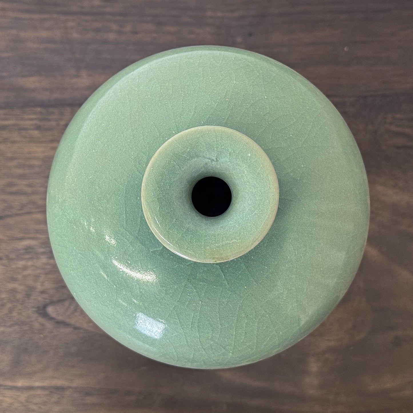 Light green ceramic vase on a wooden surface