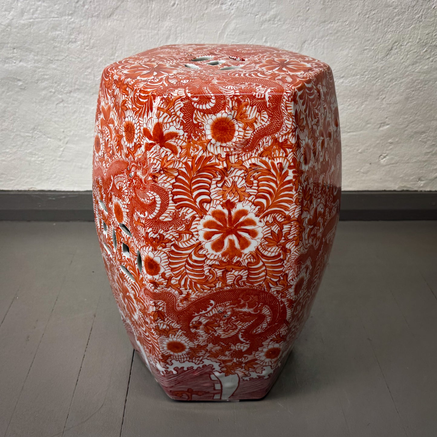 Decorative ceramic stool with red and white floral patterns on a plain background
