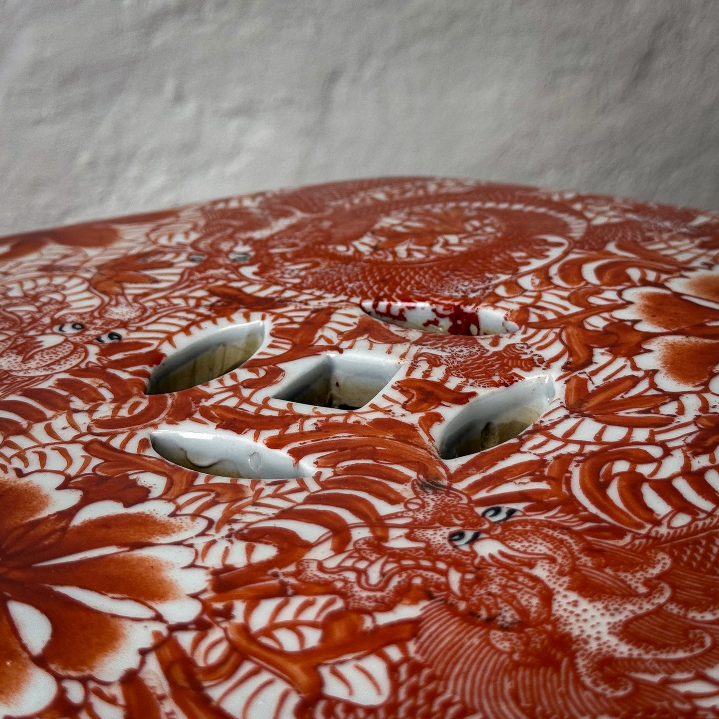 Decorative red and white ceramic plate with intricate patterns on a neutral background