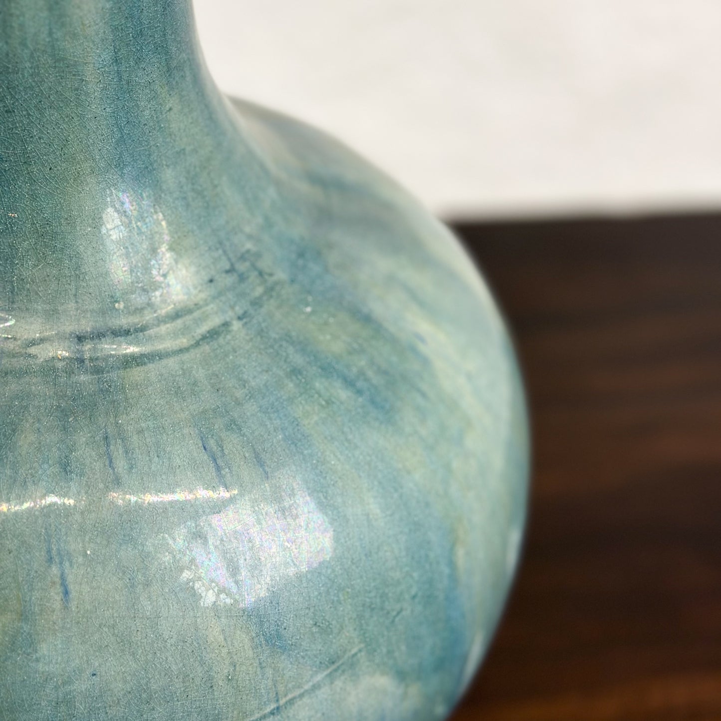 A ceramic globular vase with a blue-green glaze, displayed against a neutral background.