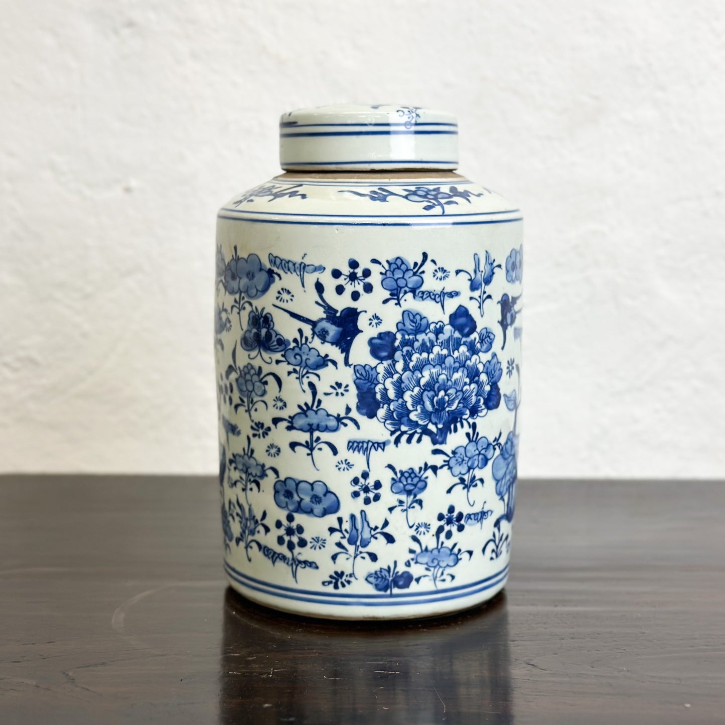 A cylindrical porcelain container with a lid, featuring a hand-painted floral design in blue and white colors.