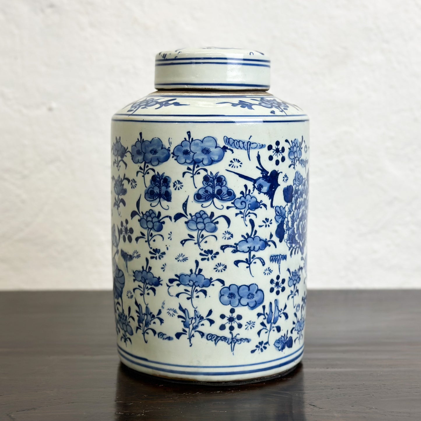 A cylindrical porcelain container with a lid, featuring a hand-painted floral design in blue and white colors.