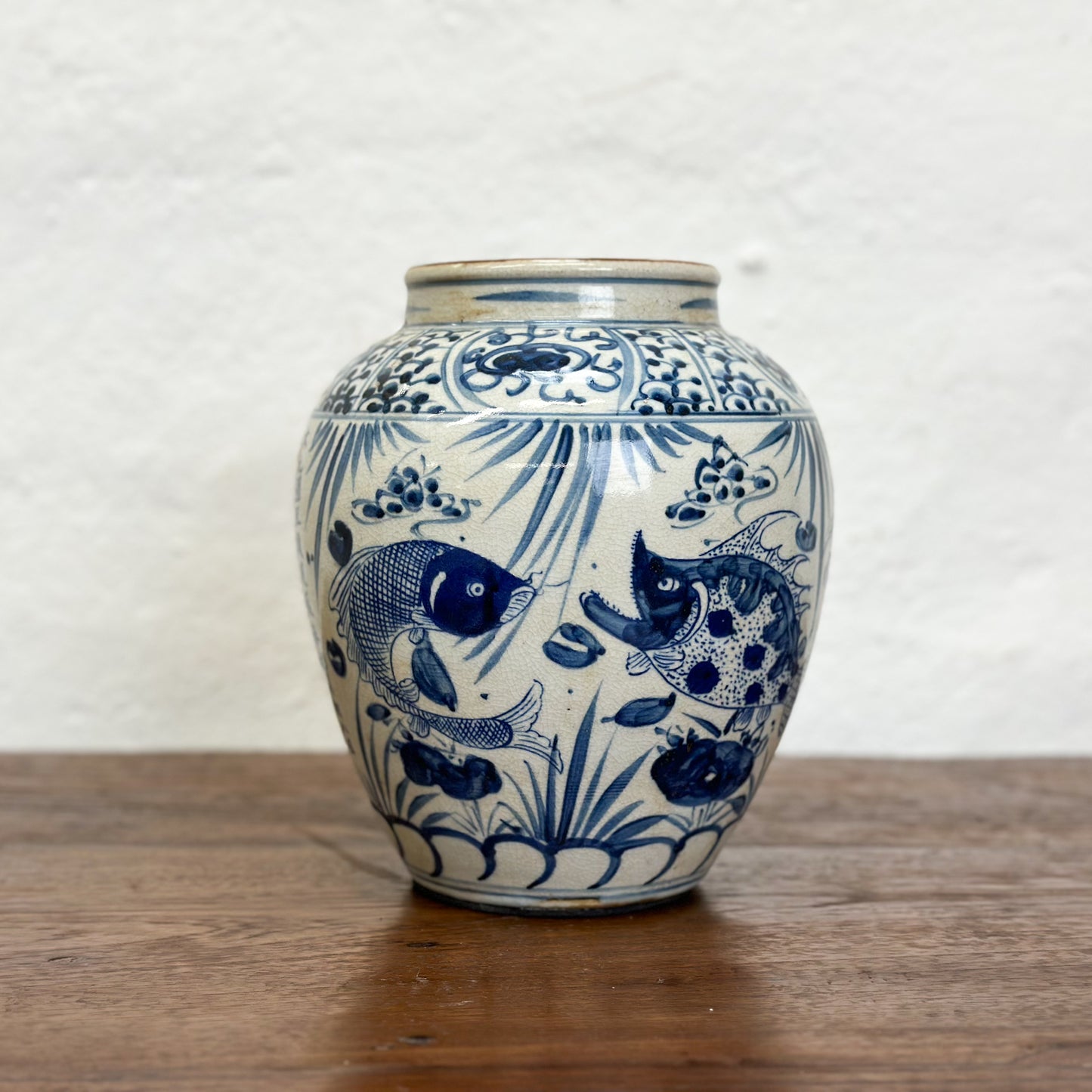 A blue and white porcelain vase with fish patterns, displayed against a neutral background.