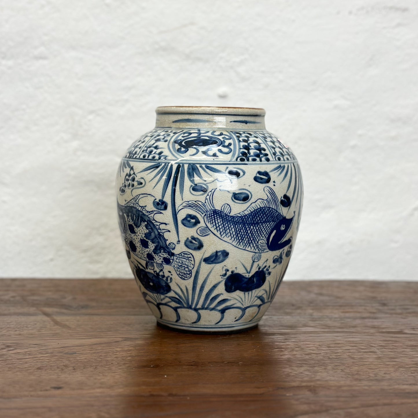 A blue and white porcelain vase with fish patterns, displayed against a neutral background.