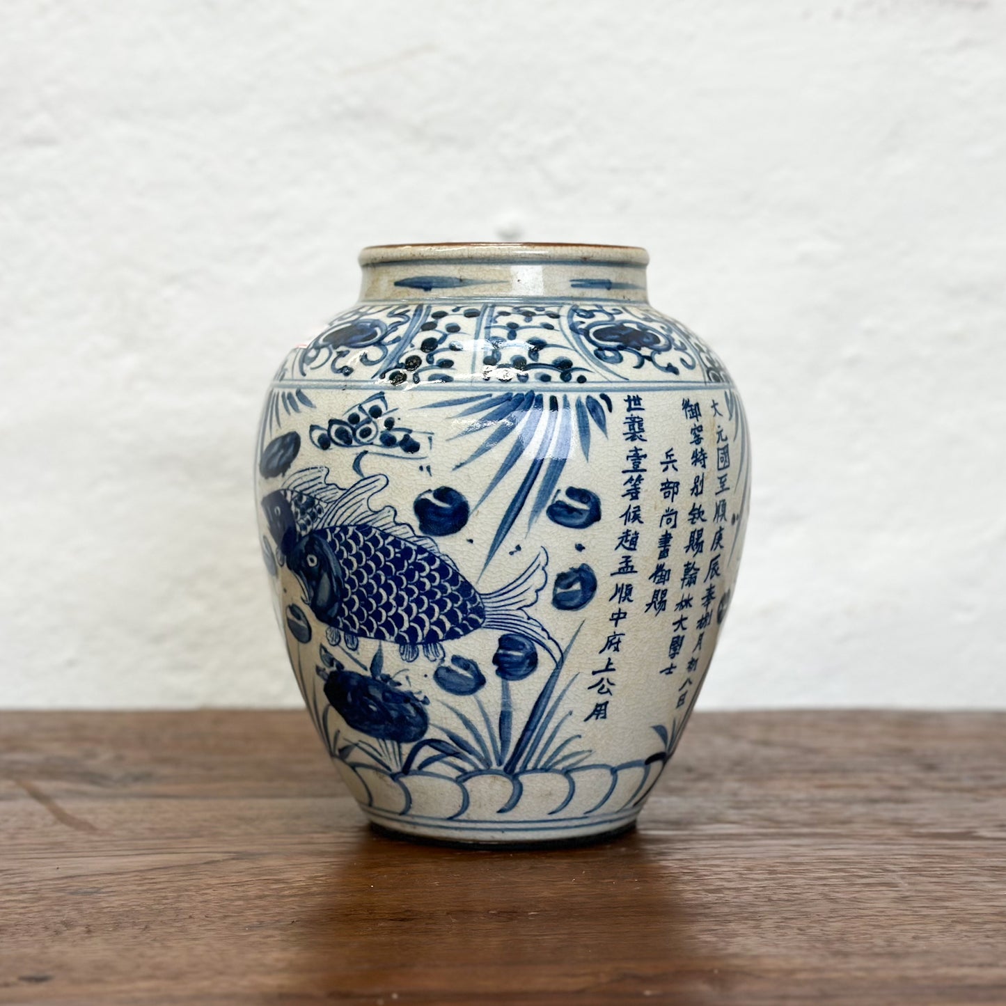A blue and white porcelain vase with fish patterns, displayed against a neutral background.