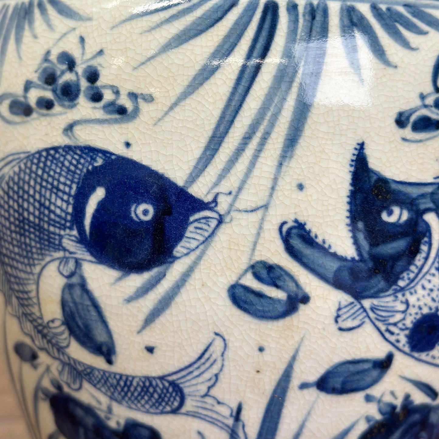 A blue and white porcelain vase with fish patterns, displayed against a neutral background.