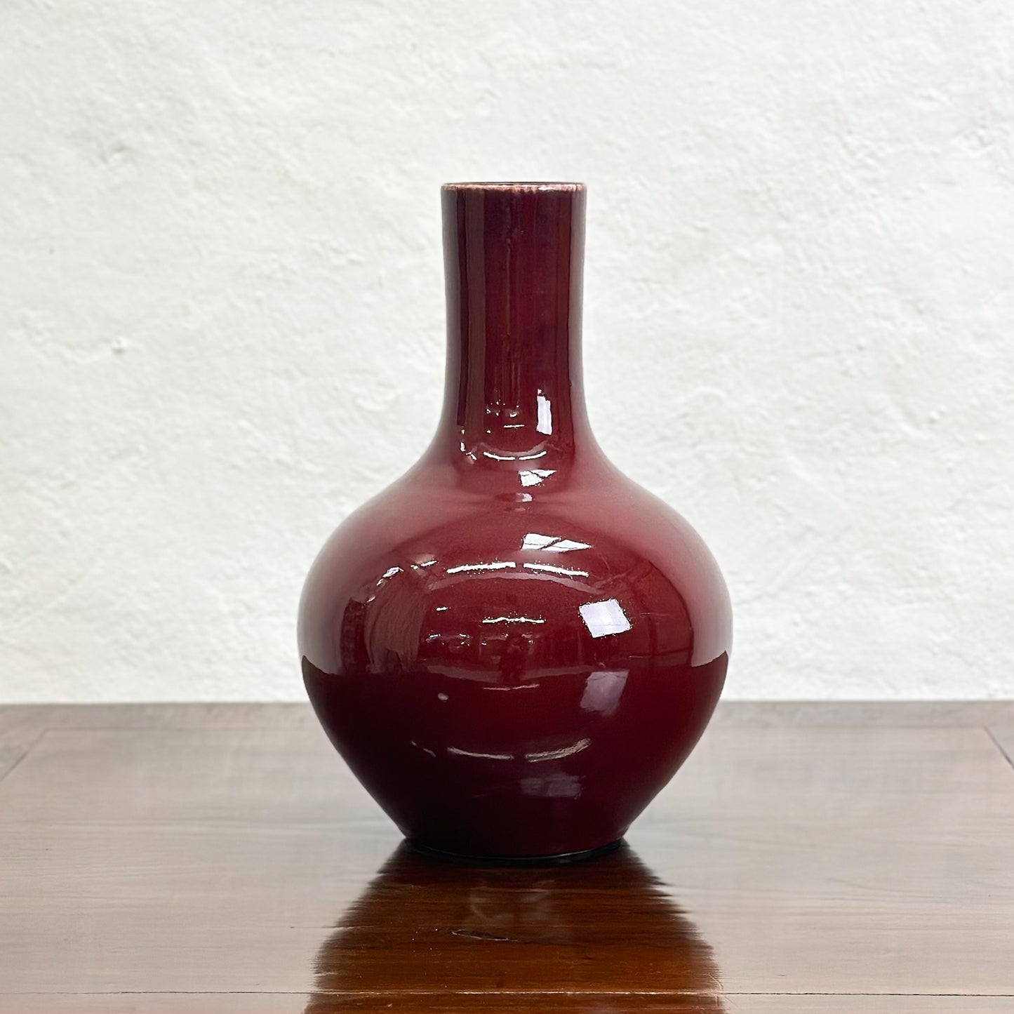 A burgundy.globular vase displayed against a neutral background.